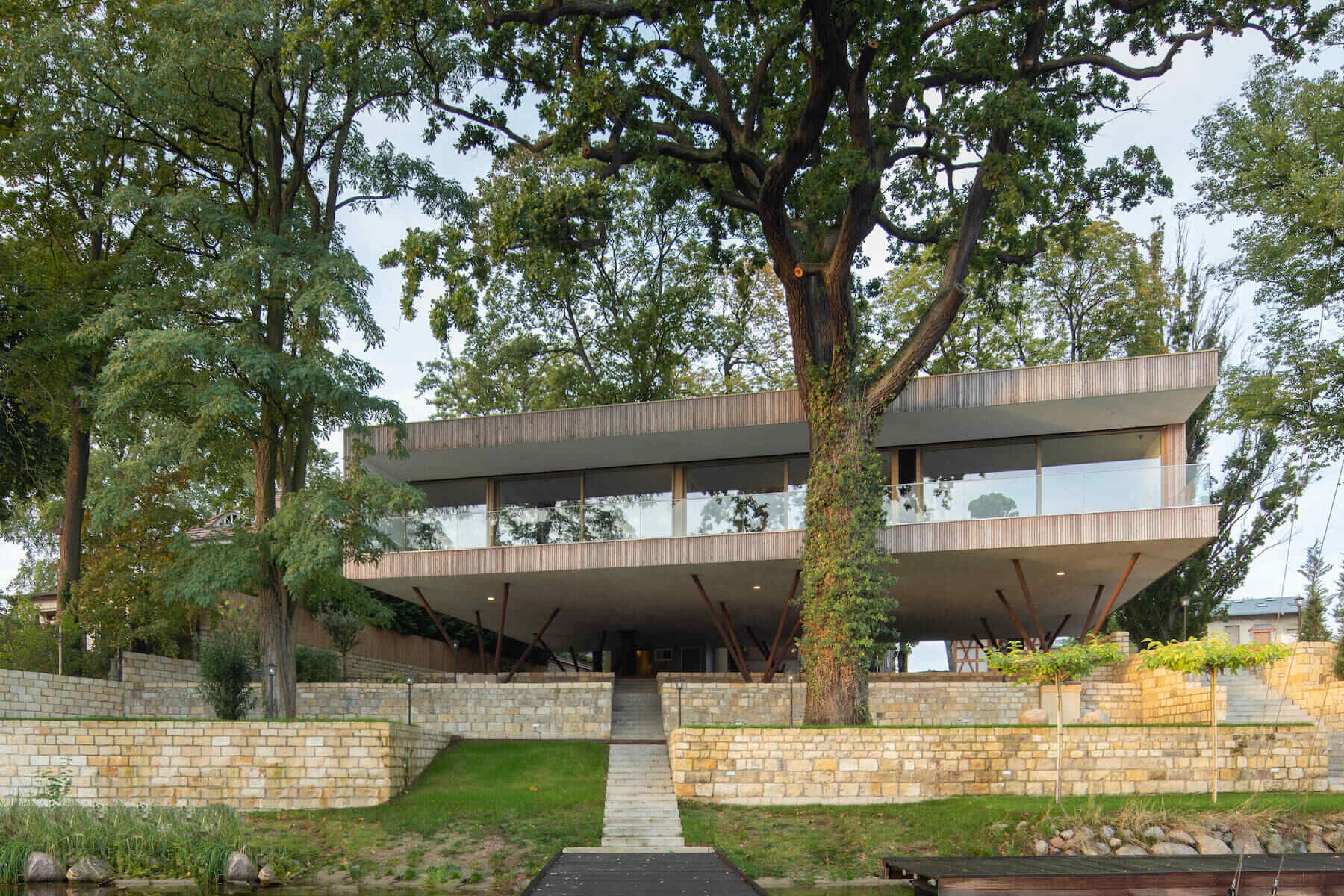A modern home in Potsdam designed on posts to protect the landscape while creating a striking elevated form above the riverfront.