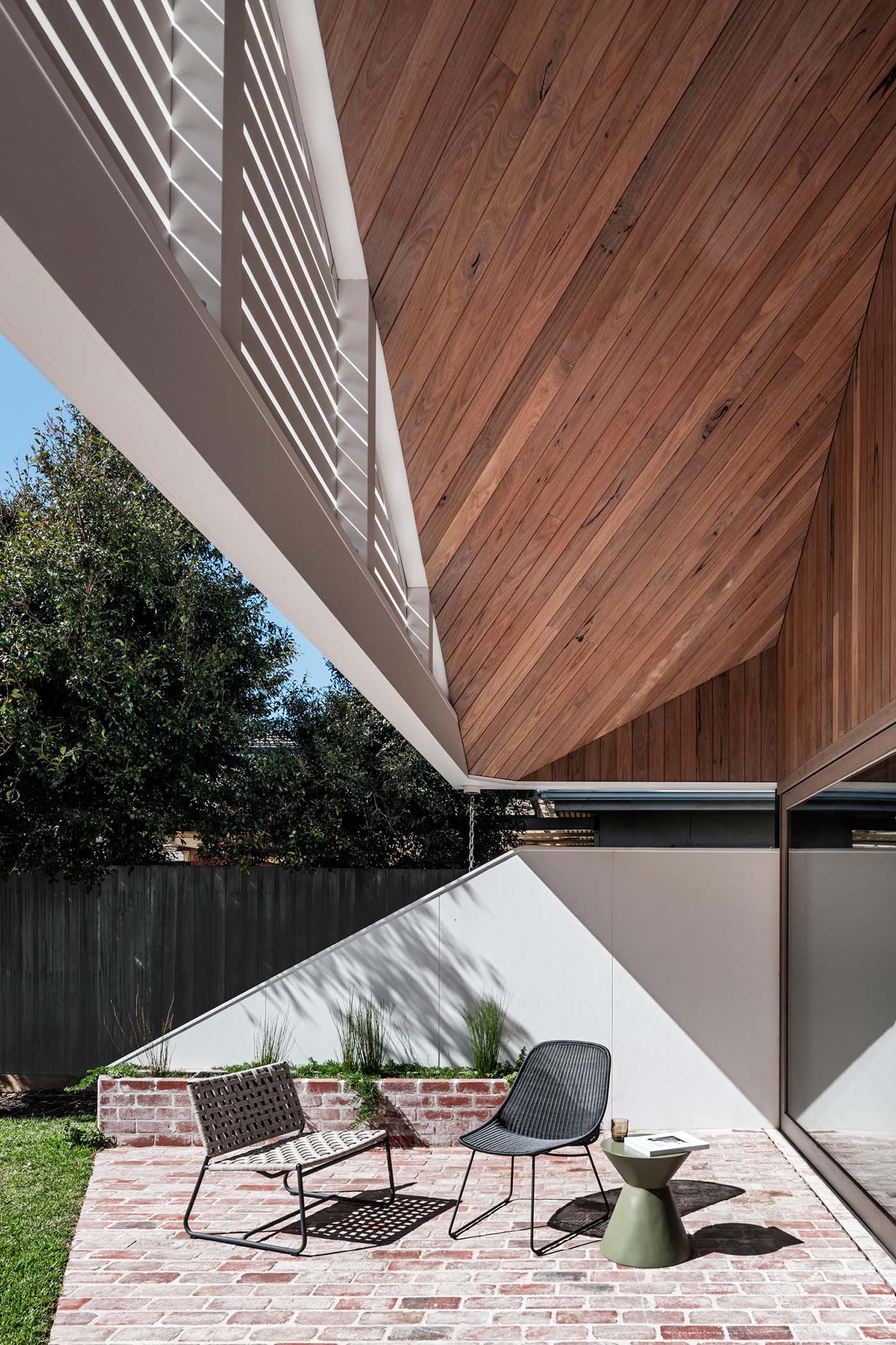 Sliding glass doors and a continuous wood ceiling connect indoor and outdoor living, creating a seamless flow between spaces.