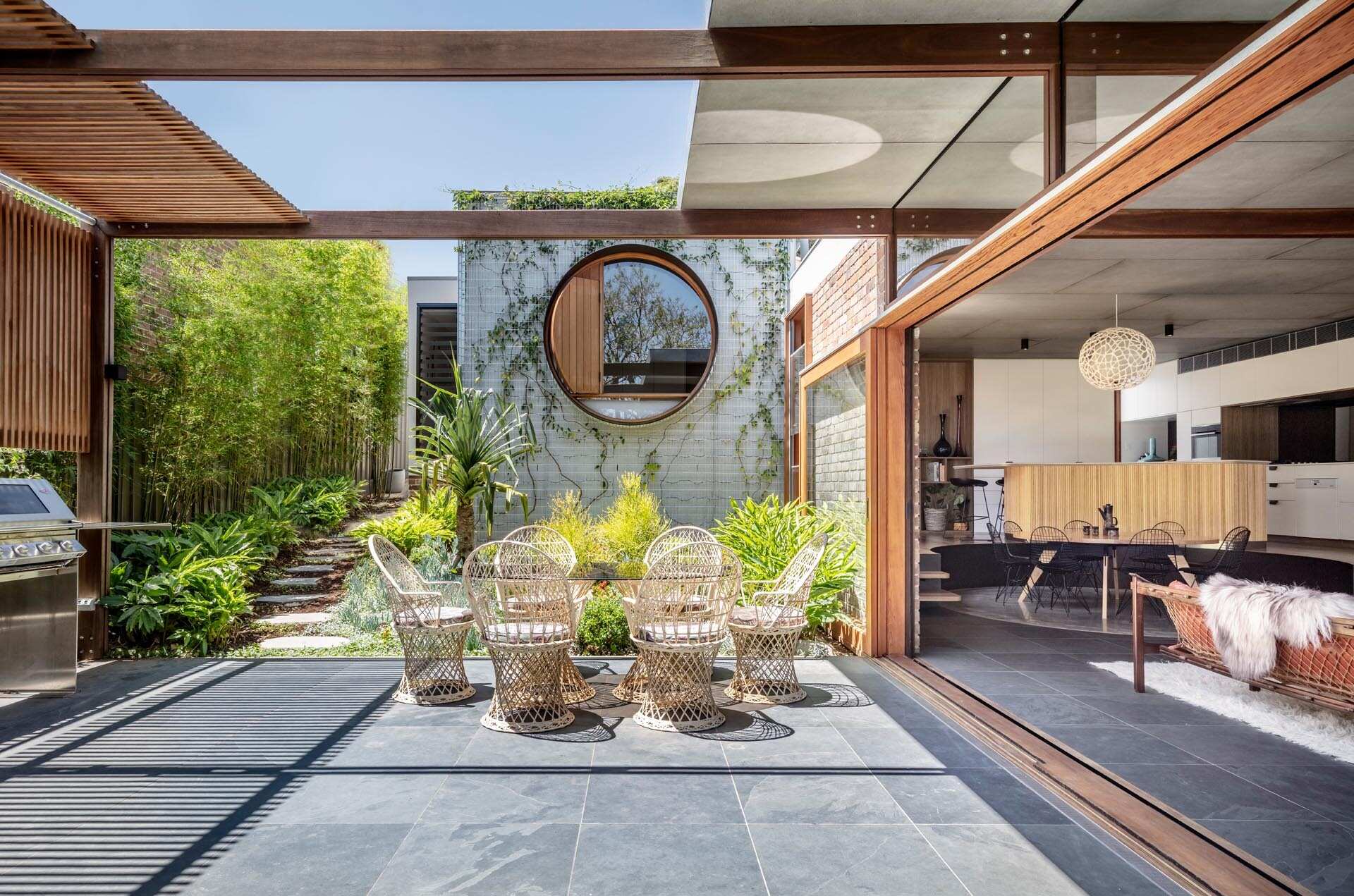 La terraza exterior parcialmente cubierta cuenta con una zona de barbacoa y comedor, diseñada para una vida interior y exterior perfecta en una casa contemporánea de Sydney.