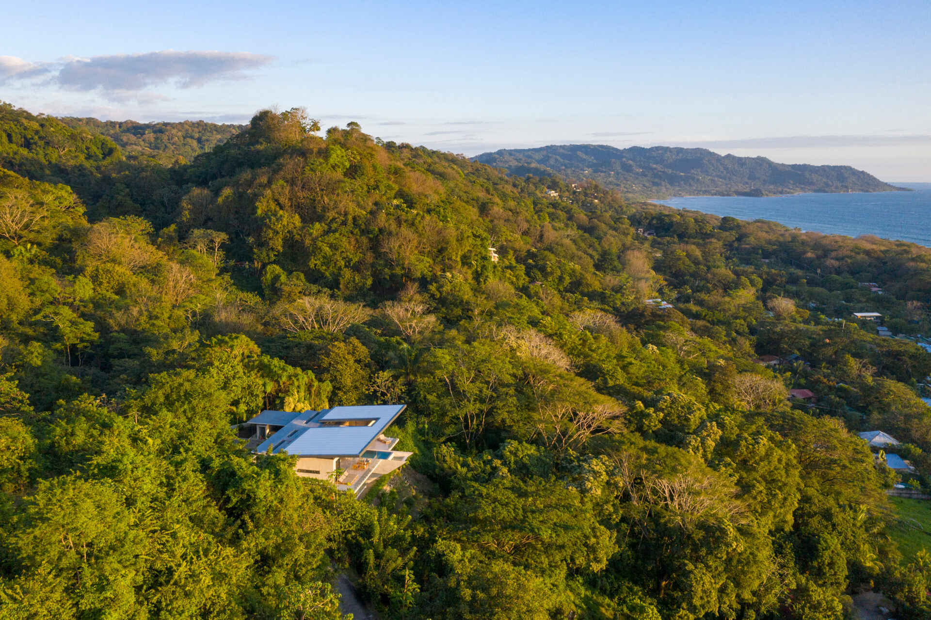 A modern hillside home in Santa Teresa, Costa Rica that hides its full size from the street before opening up to expansive ocean views.