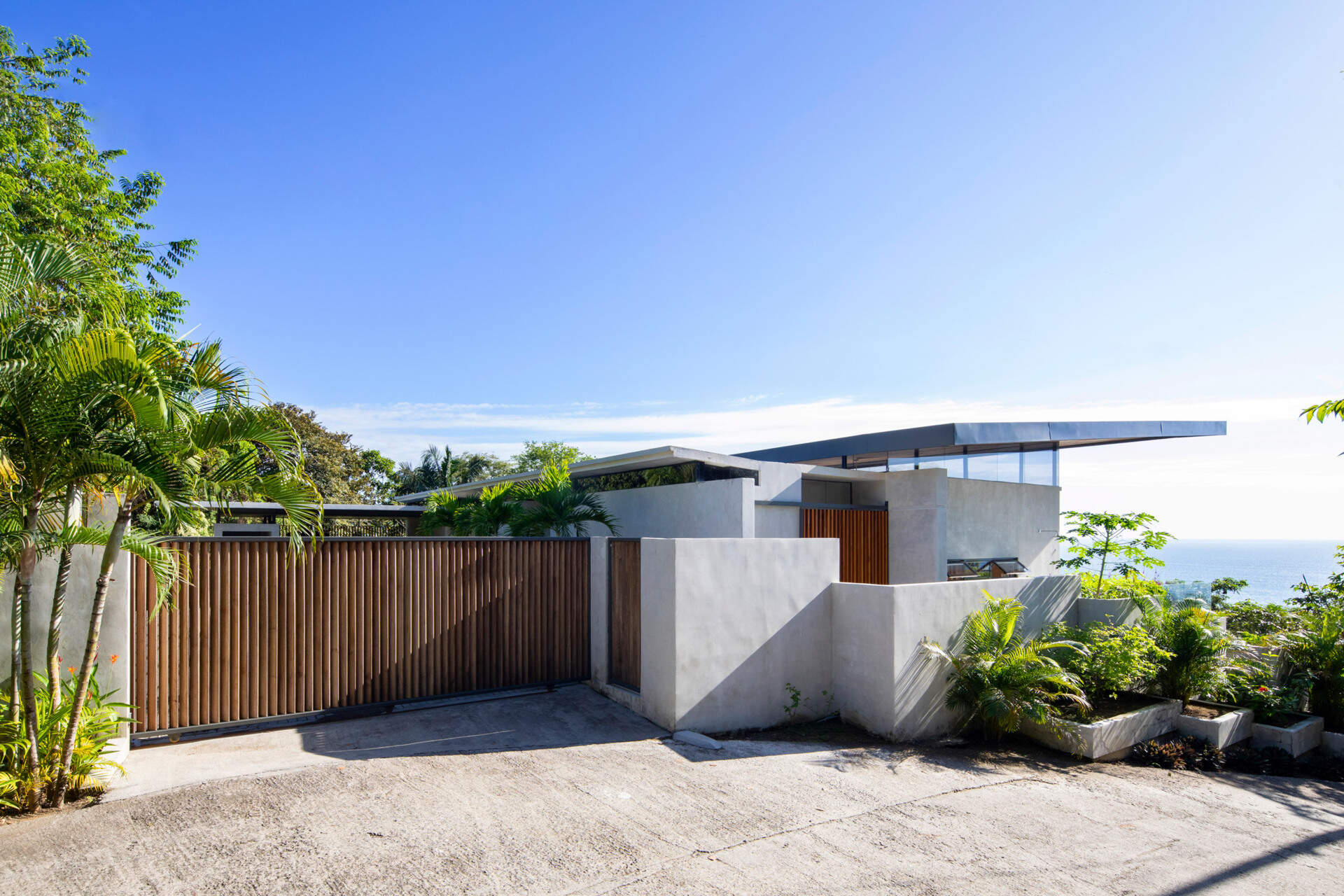 A sweeping wood-lined roof that protects the home, frames the pool, and helps keep the interior cool in a tropical climate.