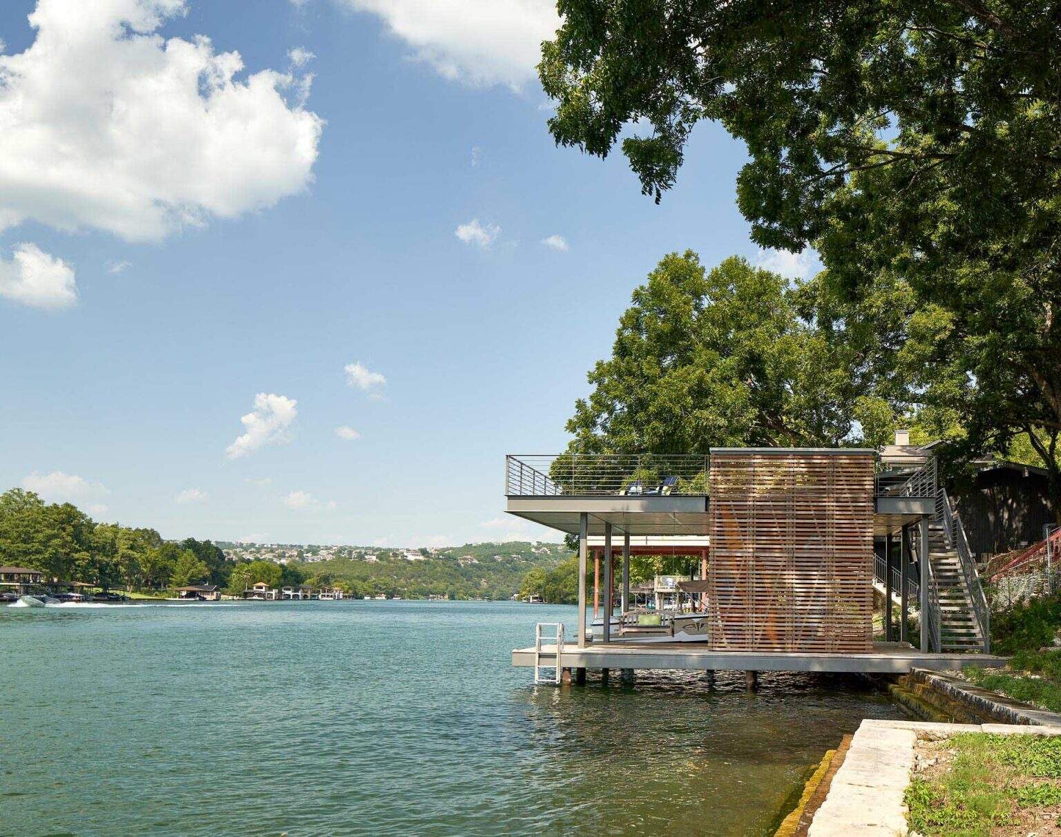 A two-level boat dock extends the home onto the water, creating a relaxed outdoor lounge space right above the lake.