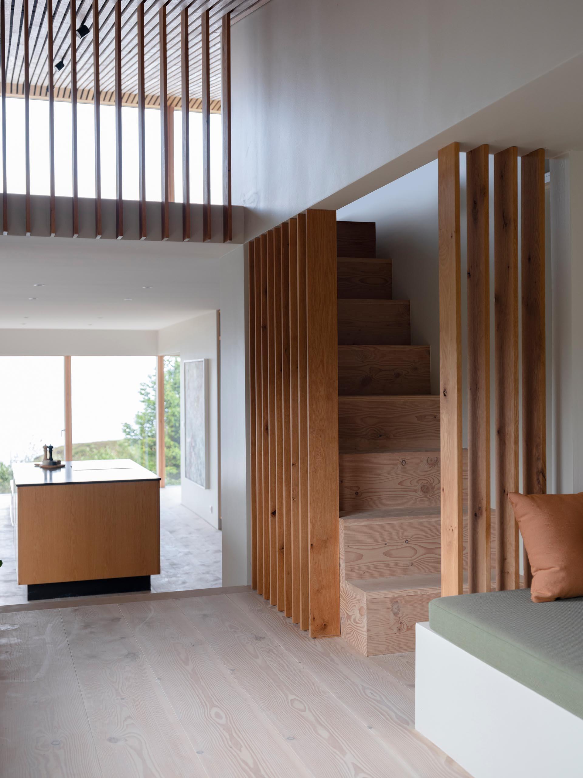 Wood stairs and slatted details create continuity throughout the interior of this modern holiday home.