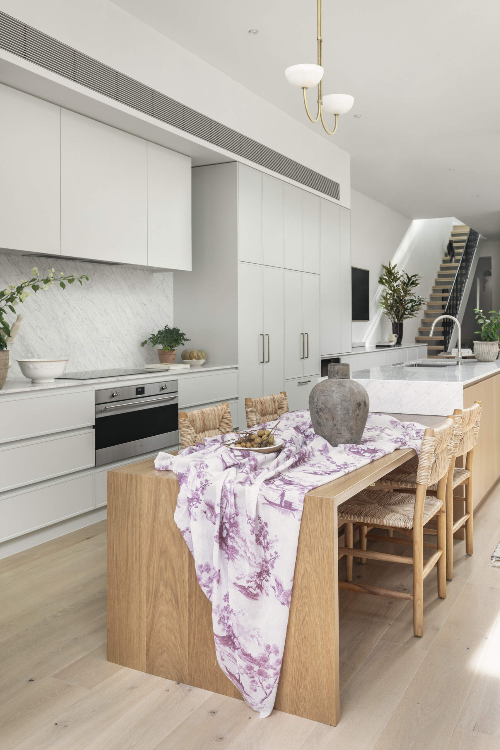 At the center of the open-plan layout, the kitchen island doubles as a dining table. It works as both a gathering point and a functional surface, linking the kitchen and living areas.