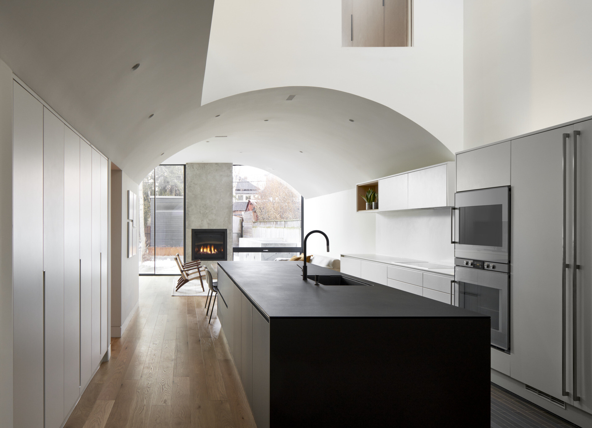 A minimalist white kitchen paired with a matte blue island creates a clean yet striking focal point under a curved ceiling.