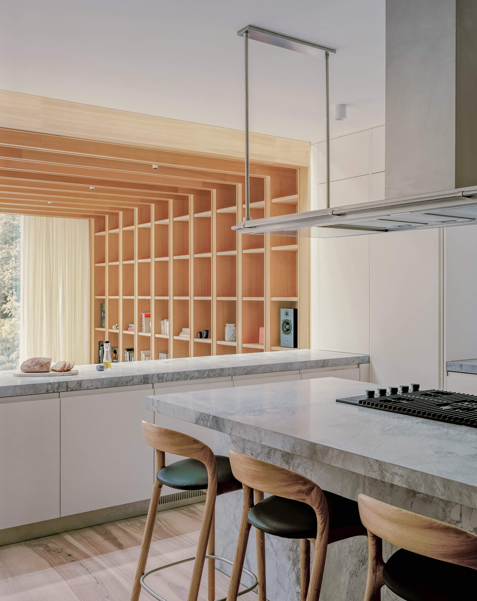 Quartzite surfaces and a central island anchor this open kitchen, designed to stay connected to both the living area and the view.