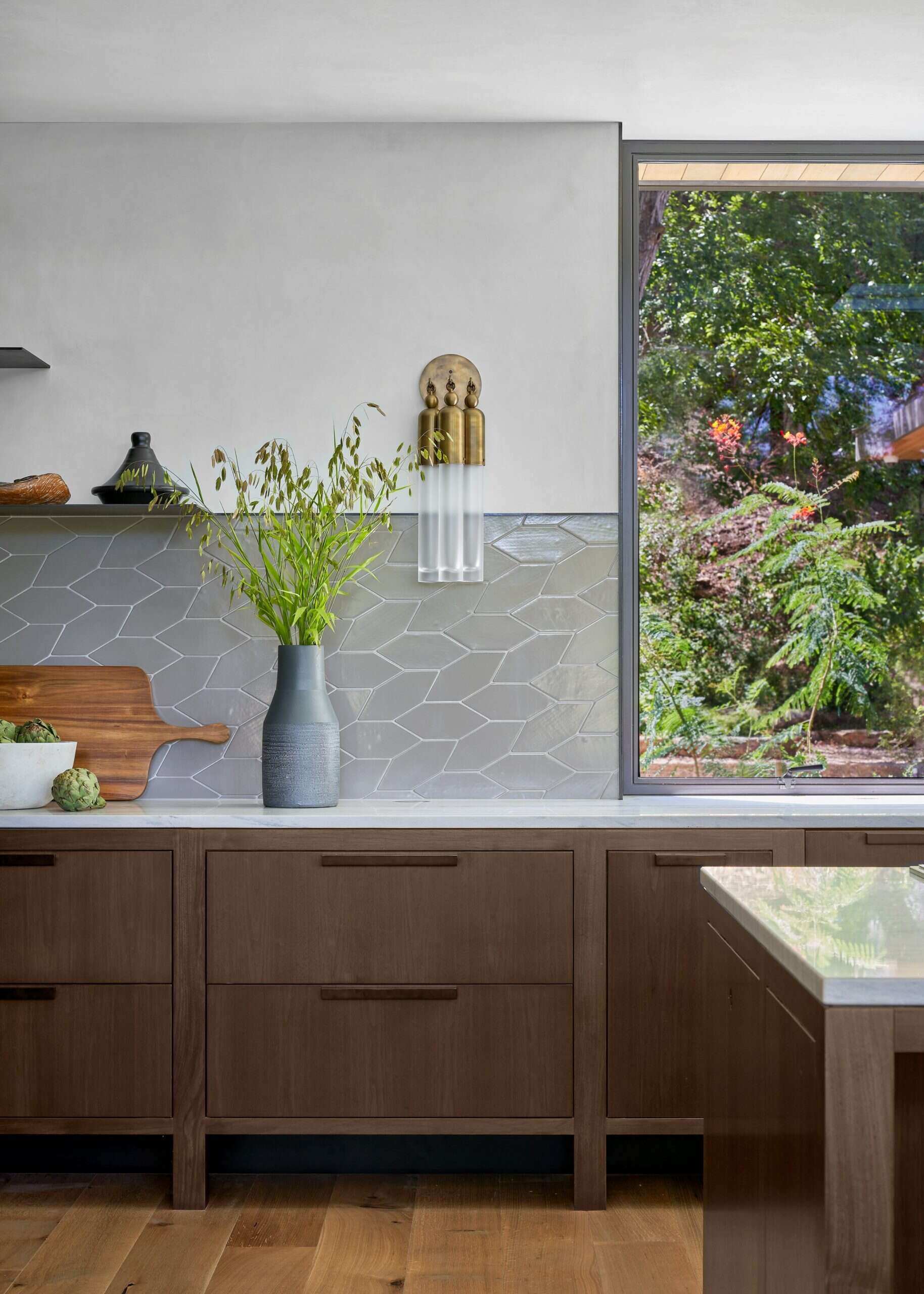 A modern kitchen features cabinetry on wooden legs, a glass-front refrigerator, and a custom armoire for coffee equipment.