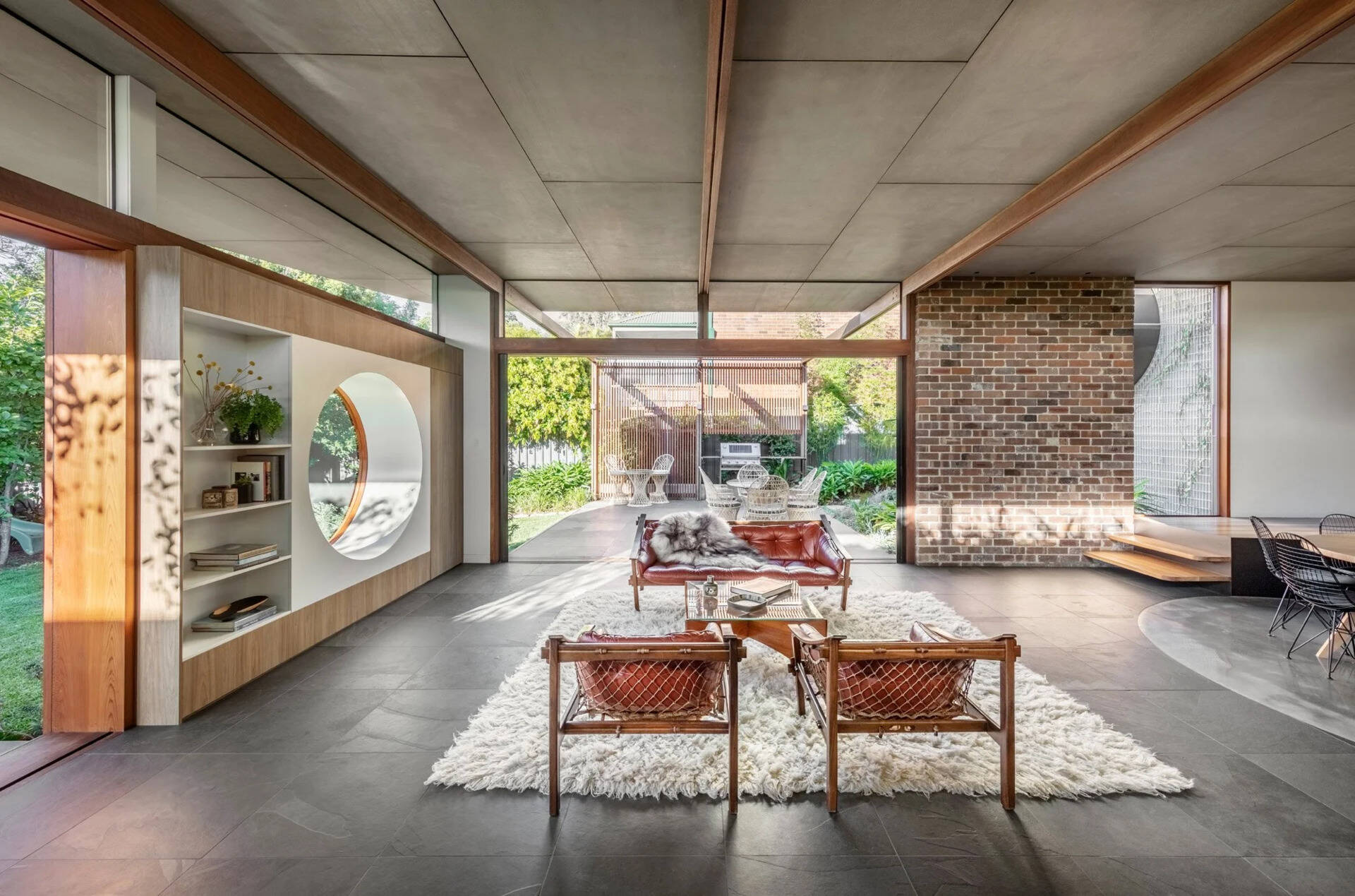 El salón cuenta con un gran ventanal redondo y puertas correderas de cristal que dan acceso directo a la terraza exterior.