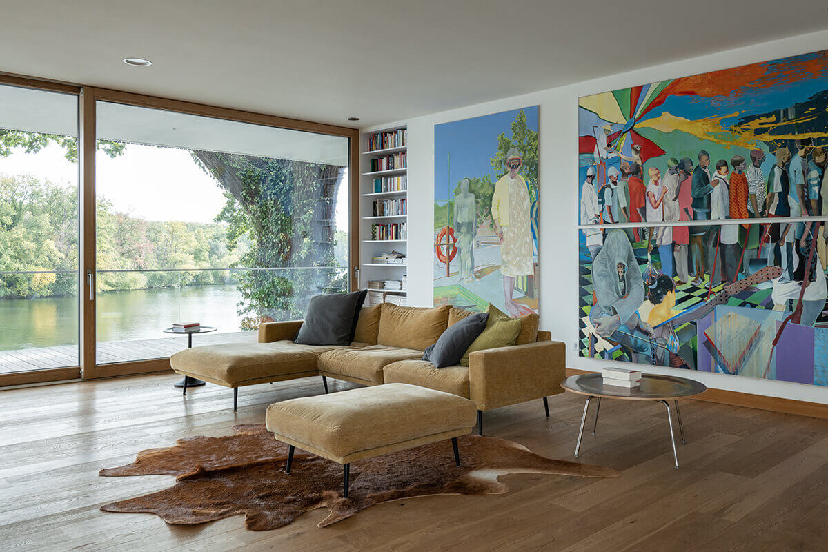 Minimal interiors meet bold artwork in this living room, where large sliding glass doors open to river views and a sleek fireplace adds warmth.