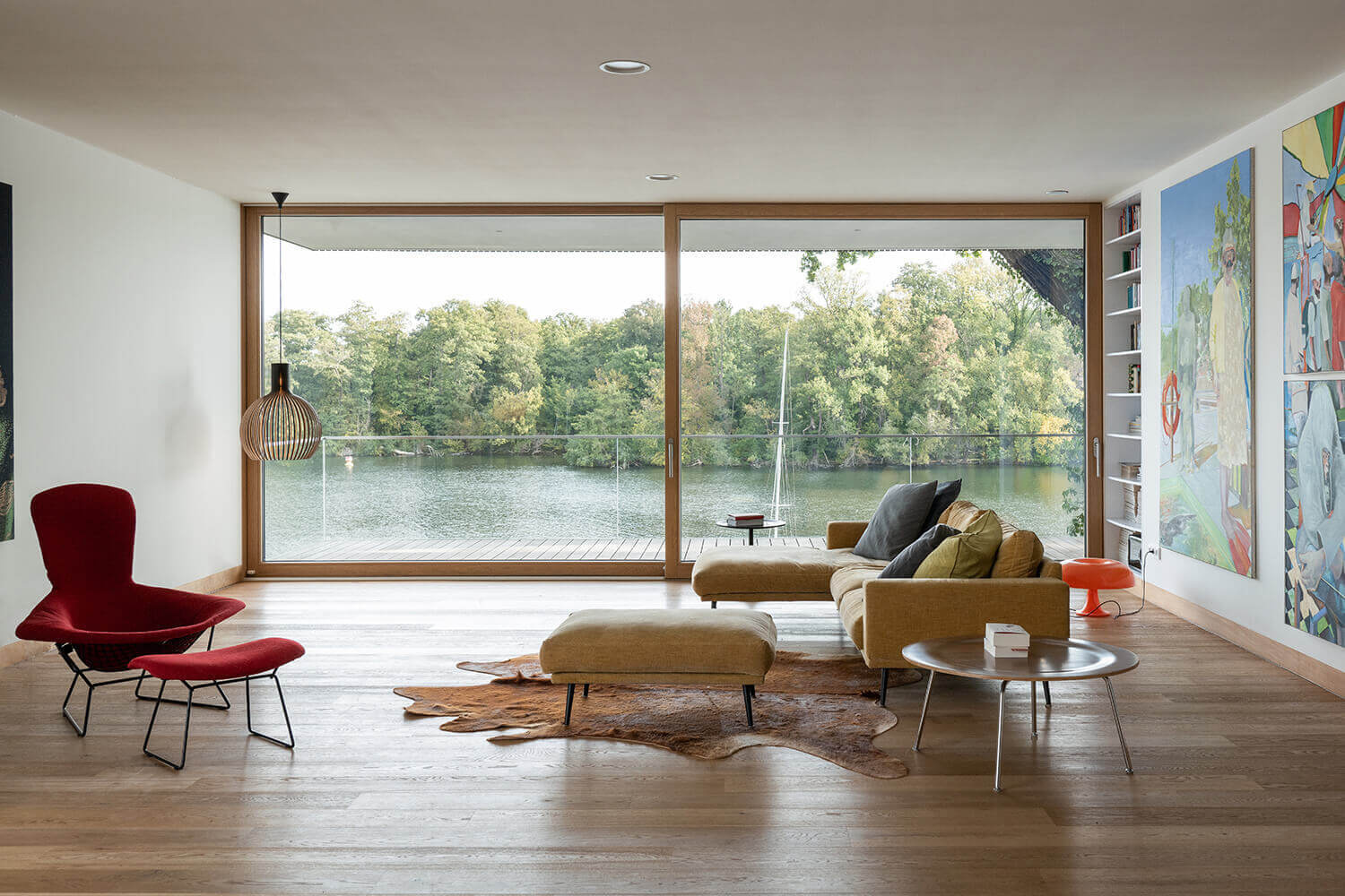 Minimal interiors meet bold artwork in this living room, where large sliding glass doors open to river views and a sleek fireplace adds warmth.
