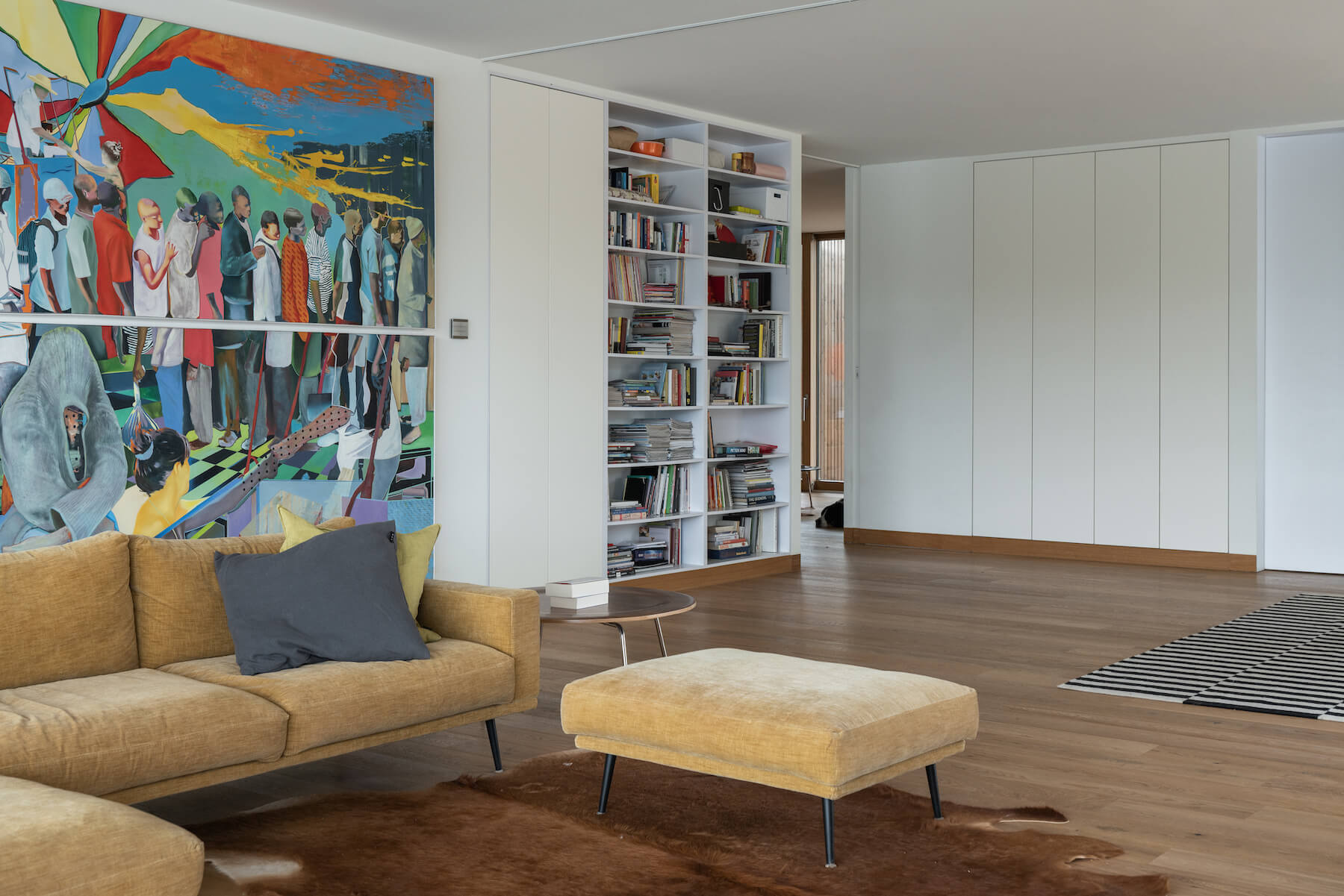 Minimal interiors meet bold artwork in this living room, where large sliding glass doors open to river views and a sleek fireplace adds warmth.