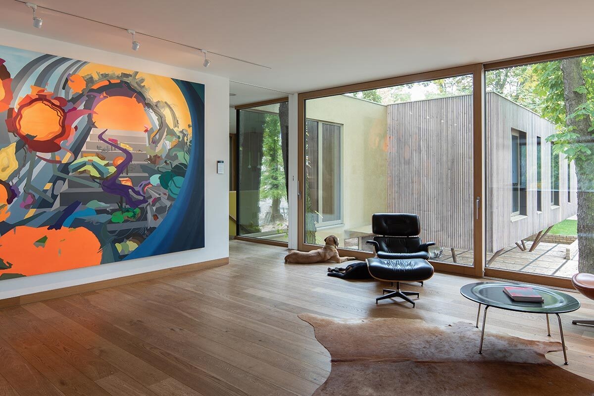 Minimal interiors meet bold artwork in this living room, where large sliding glass doors open to river views and a sleek fireplace adds warmth.