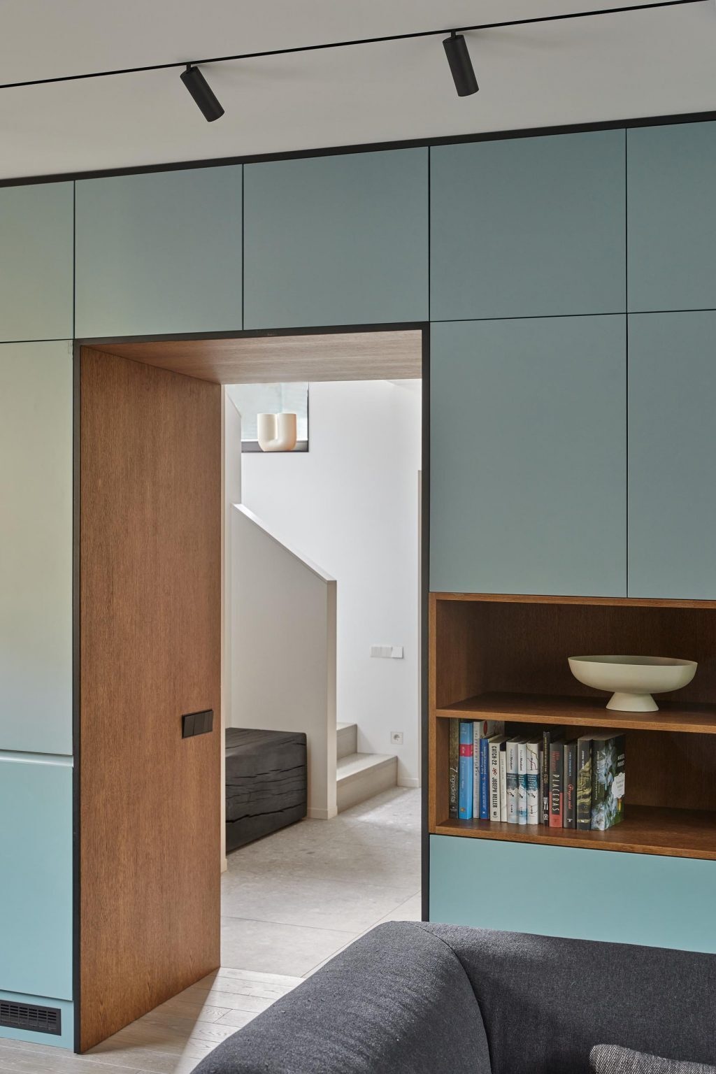 Muted mint green cabinetry pairs with wood shelving and black accents for a clean, modern kitchen look.