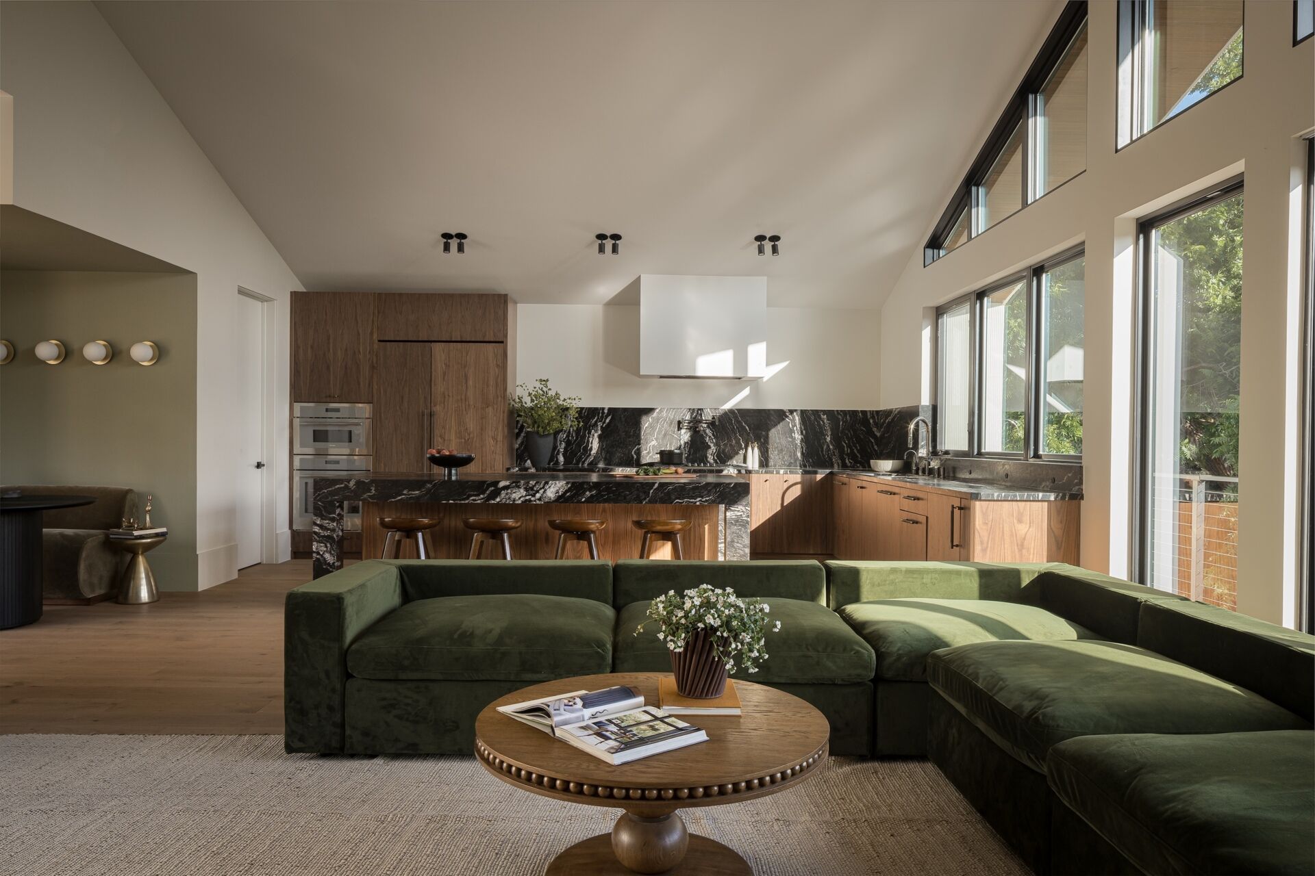 At the rear, the living room opens toward dense greenery along the edge of the lot. A large window wall frames these views, giving the space a calm outlook while maintaining privacy from nearby homes.