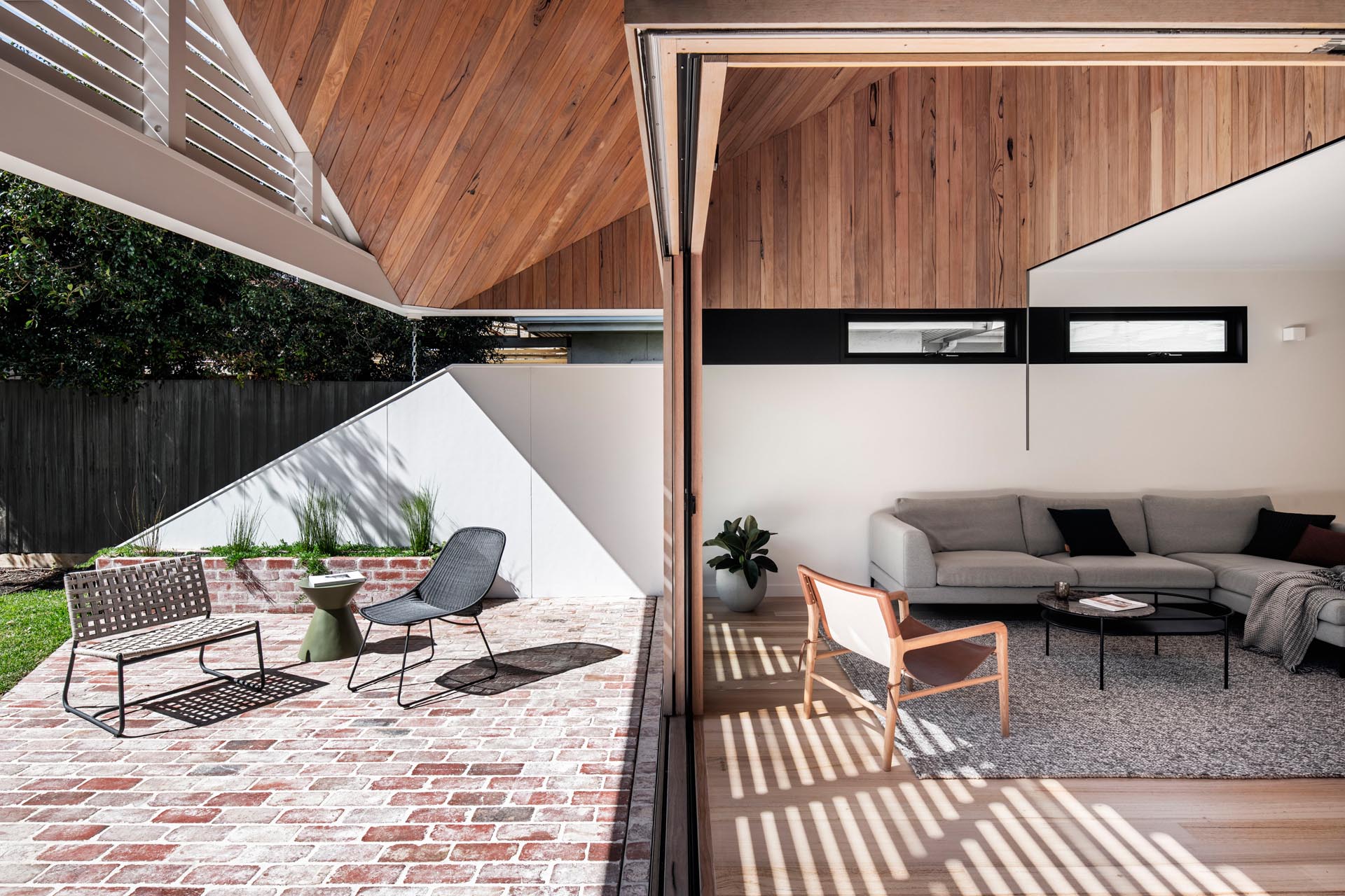 Sliding glass doors and a continuous wood ceiling connect indoor and outdoor living, creating a seamless flow between spaces.