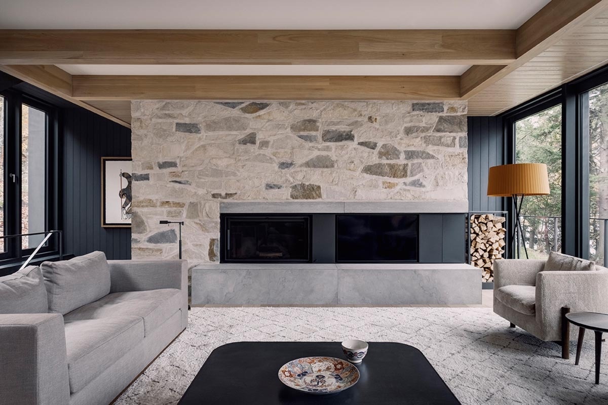 A cozy living room combines wood ceilings, a black fireplace, and a stone wall to create a rich mix of textures in a modern setting.