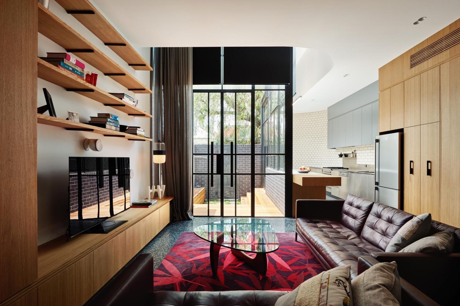 A modern living room with timber shelving, built-in storage, and polished concrete floors with underfloor heating.