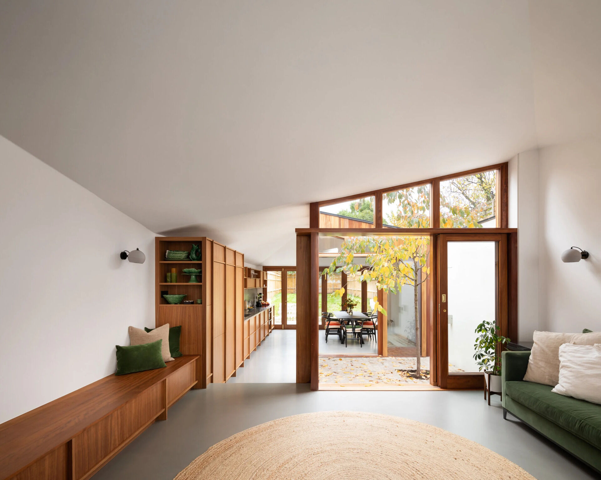 A small courtyard with a tree sits between rooms, framed by sliding glass doors for a calm indoor-outdoor connection.