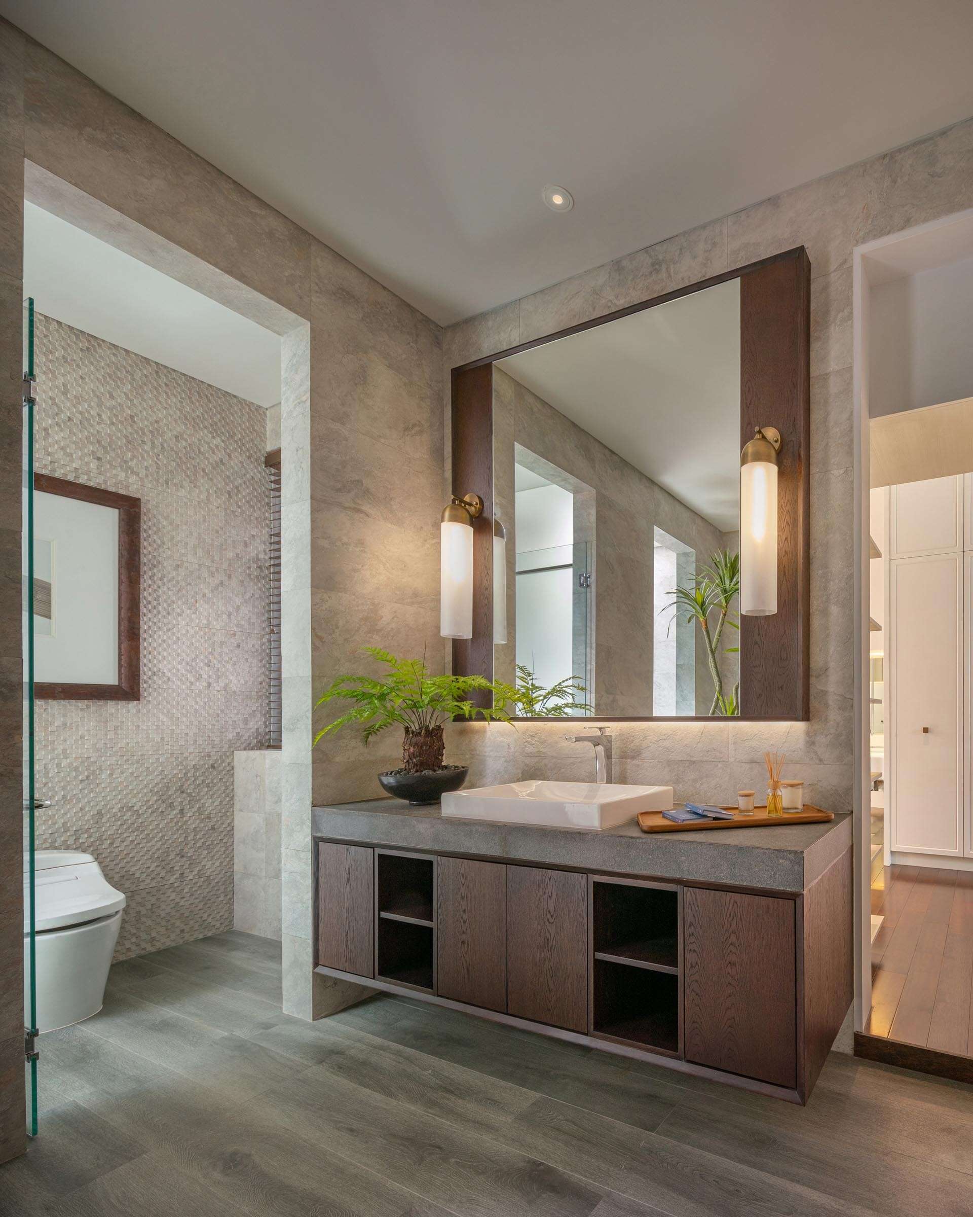 A modern bathroom with a floating wood vanity, concrete countertop, and freestanding tub.