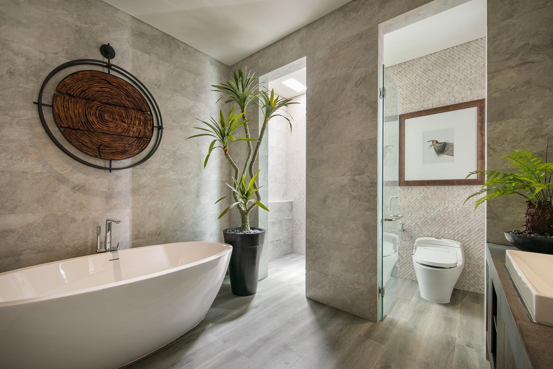 A modern bathroom with a floating wood vanity, concrete countertop, and freestanding tub.