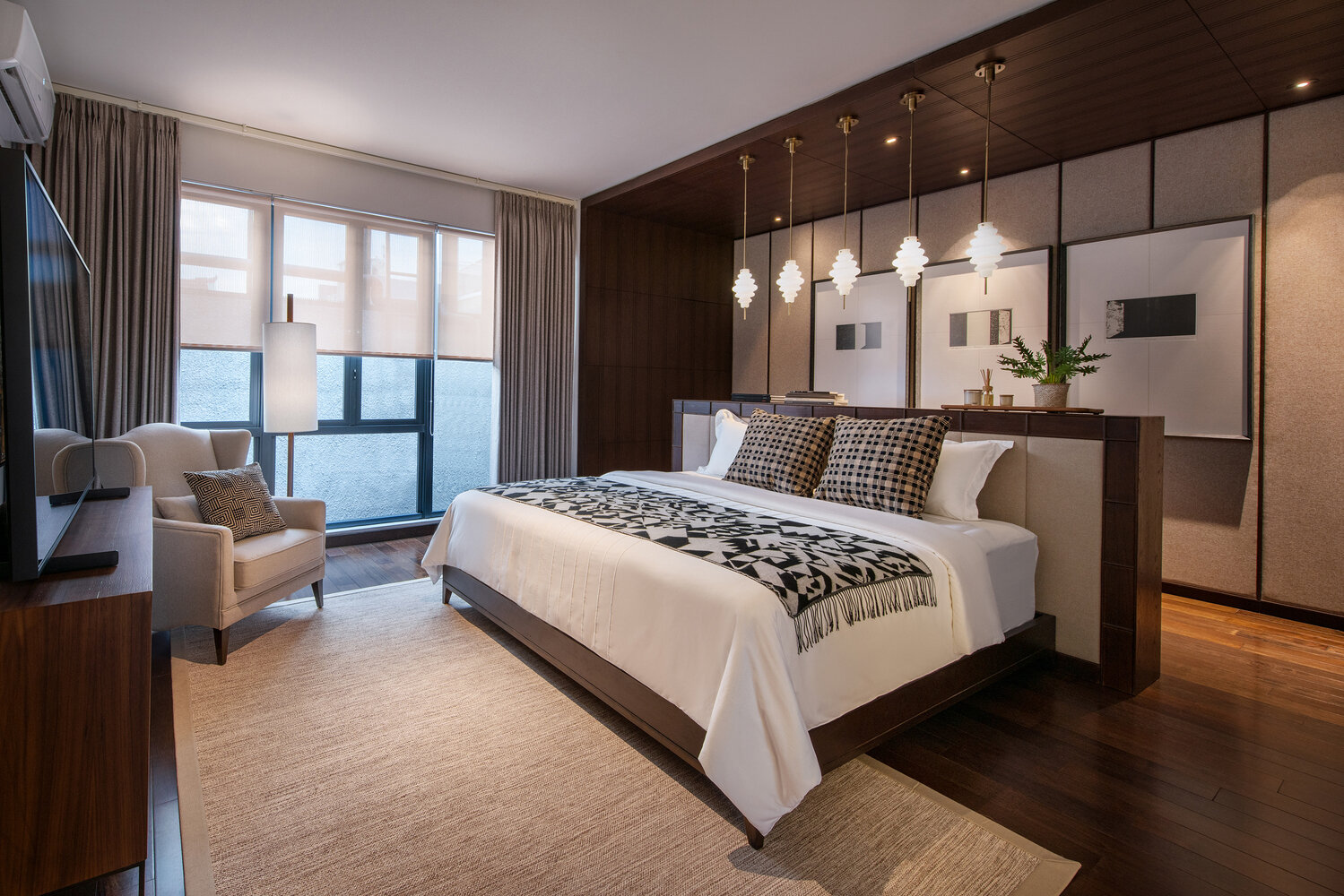 A minimalist bedroom with a central bed, pendant lighting, and layered artwork for a calm, balanced look.