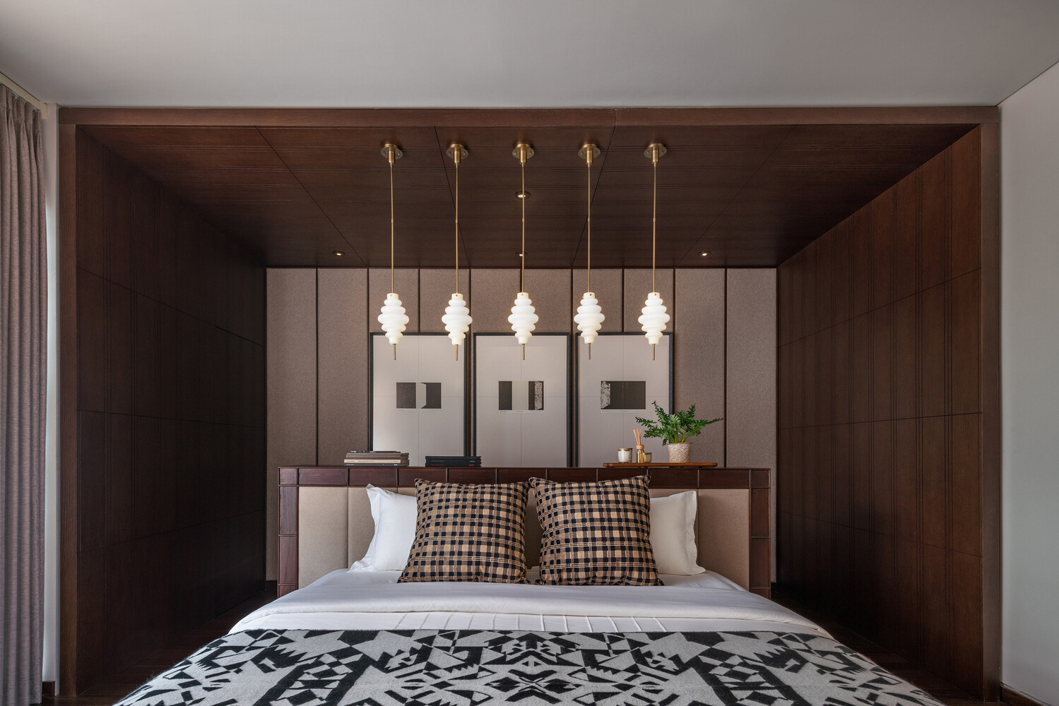 A minimalist bedroom with a central bed, pendant lighting, and layered artwork for a calm, balanced look.