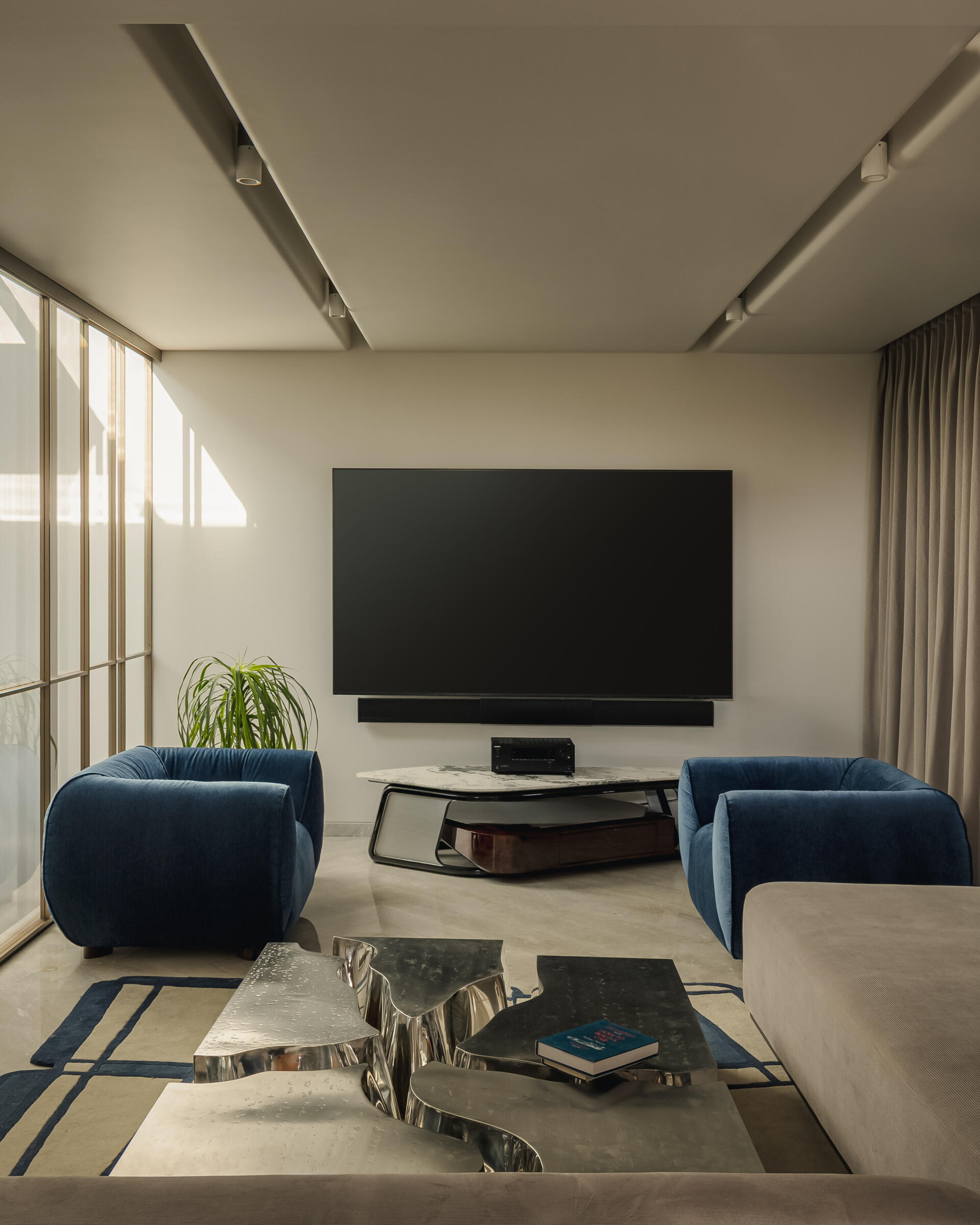Up on the second floor, a den features one of the most unique elements in the house, a split table crafted in two different stainless steel finishes. As light and screen reflections shift, the table changes with it, creating a dynamic focal point.