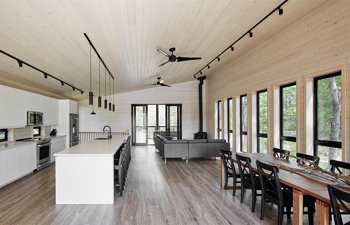 An open-plan upper level with a fireplace lounge, multiple dining tables, and a bold black-and-white kitchen designed for large family gatherings.