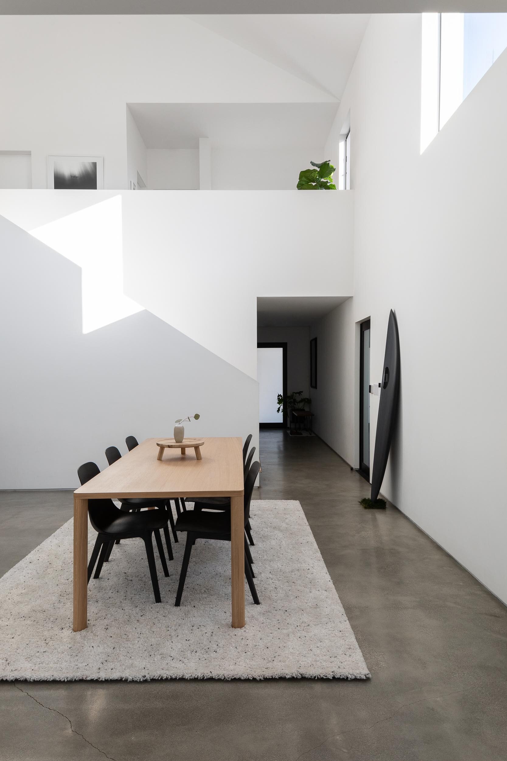 Bright white walls, concrete floors, and a double-height living space define this open plan modern interior.