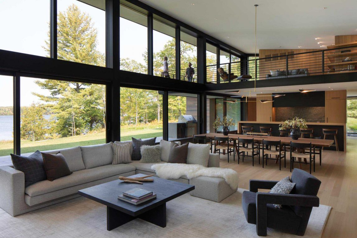 El luminoso salón cuenta con ventanales con vistas al lago y acceso perfecto a la terraza exterior y a la cocina.
