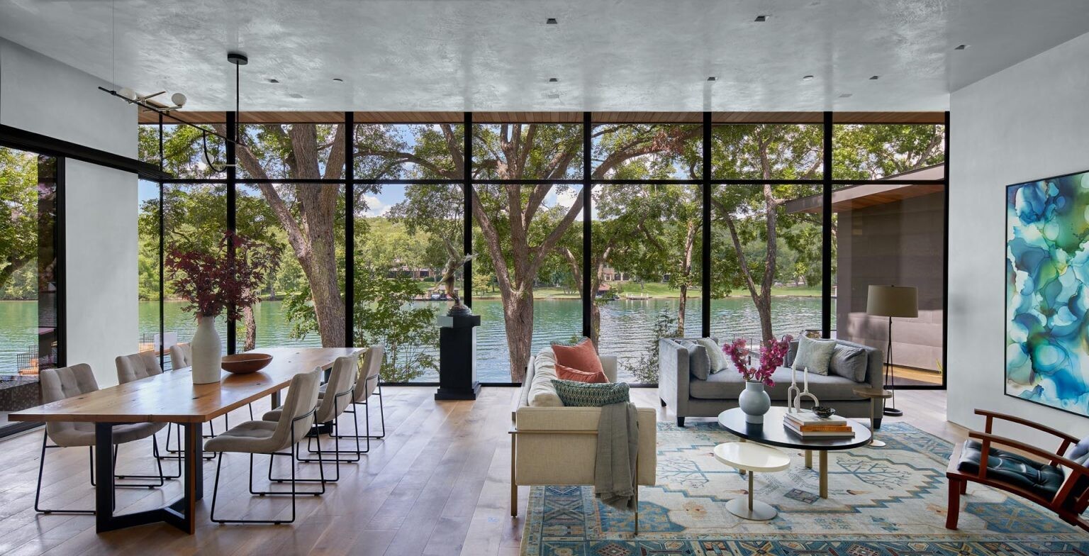 Floor-to-ceiling windows open the living and dining spaces to the outdoors, filling the home with natural light and uninterrupted lake views.