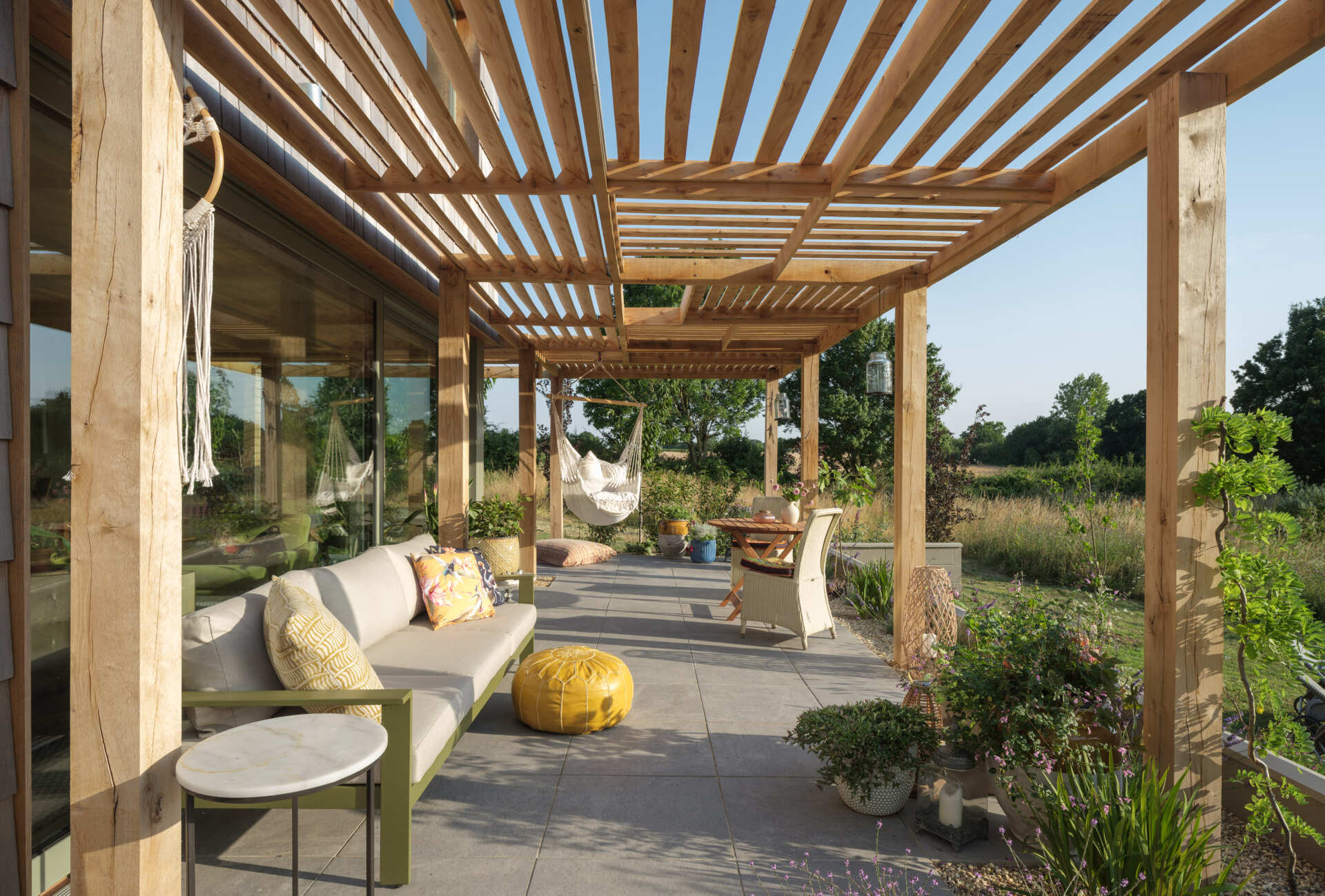 On the garden-facing side, the house extends outward, creating direct access to outdoor areas that act as an extension of the interior. The patio becomes a key point of connection, linking indoor spaces with the open landscape beyond.