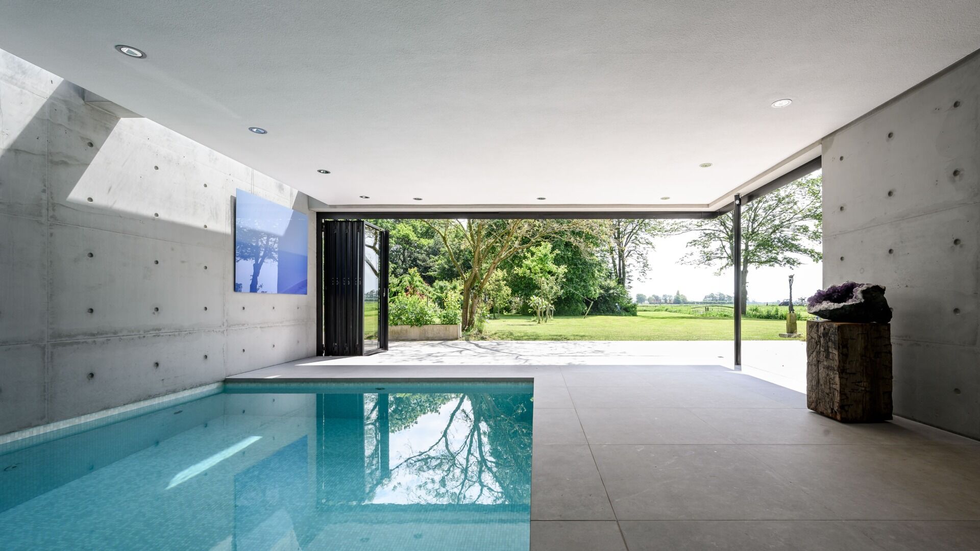 Llamativa extensión de bienestar con piscina, sauna y paredes de cristal plegables con acceso total a la terraza exterior.