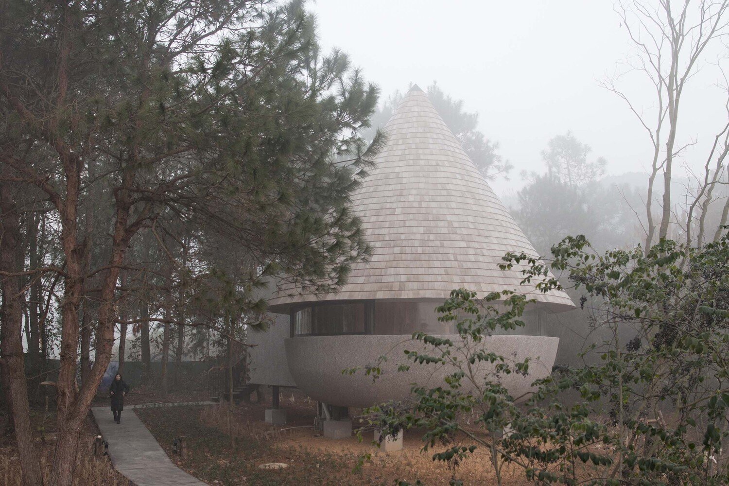 This cone-shaped roof clad in wood shingles gives the cabin a bold identity while still fitting naturally within the forest.