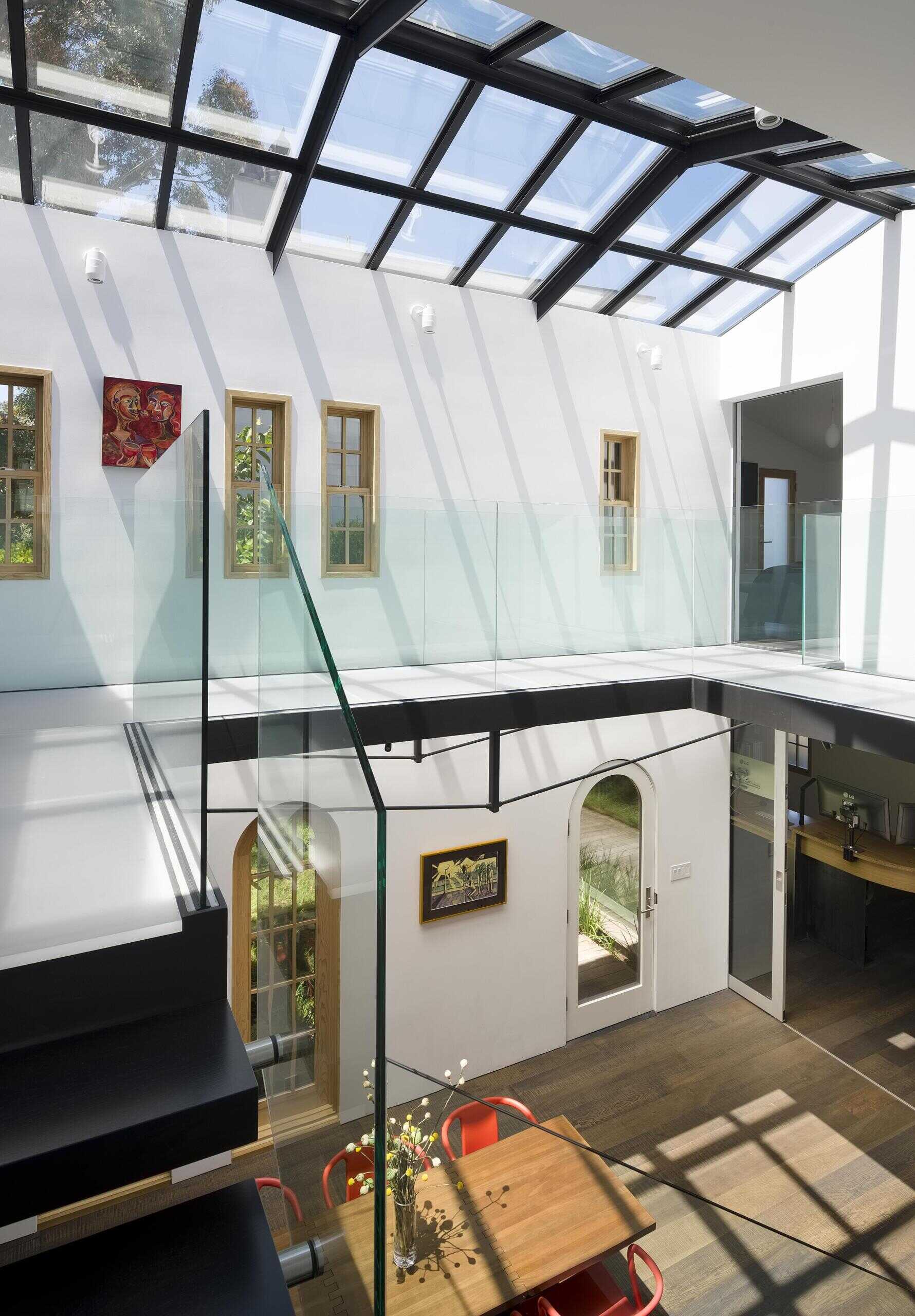 A modern interior bridge with acrylic flooring overlooking a double-height atrium, adding lightness and connection.