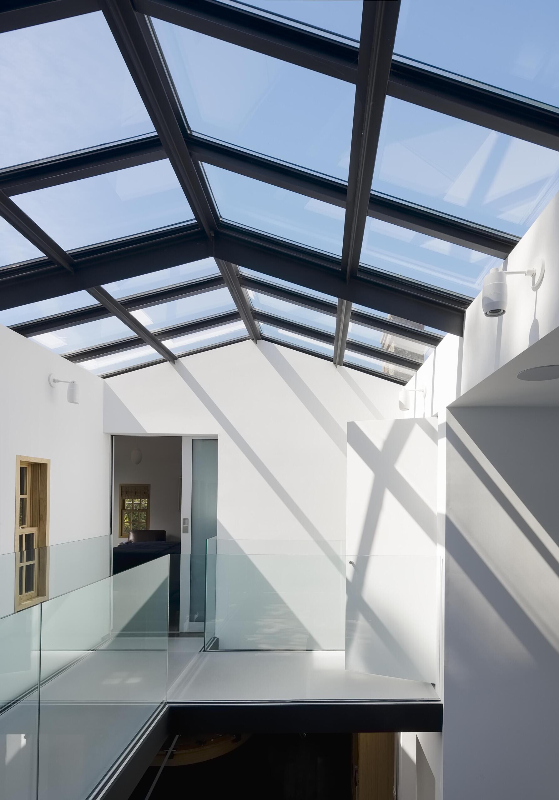 A modern interior bridge with acrylic flooring overlooking a double-height atrium, adding lightness and connection.