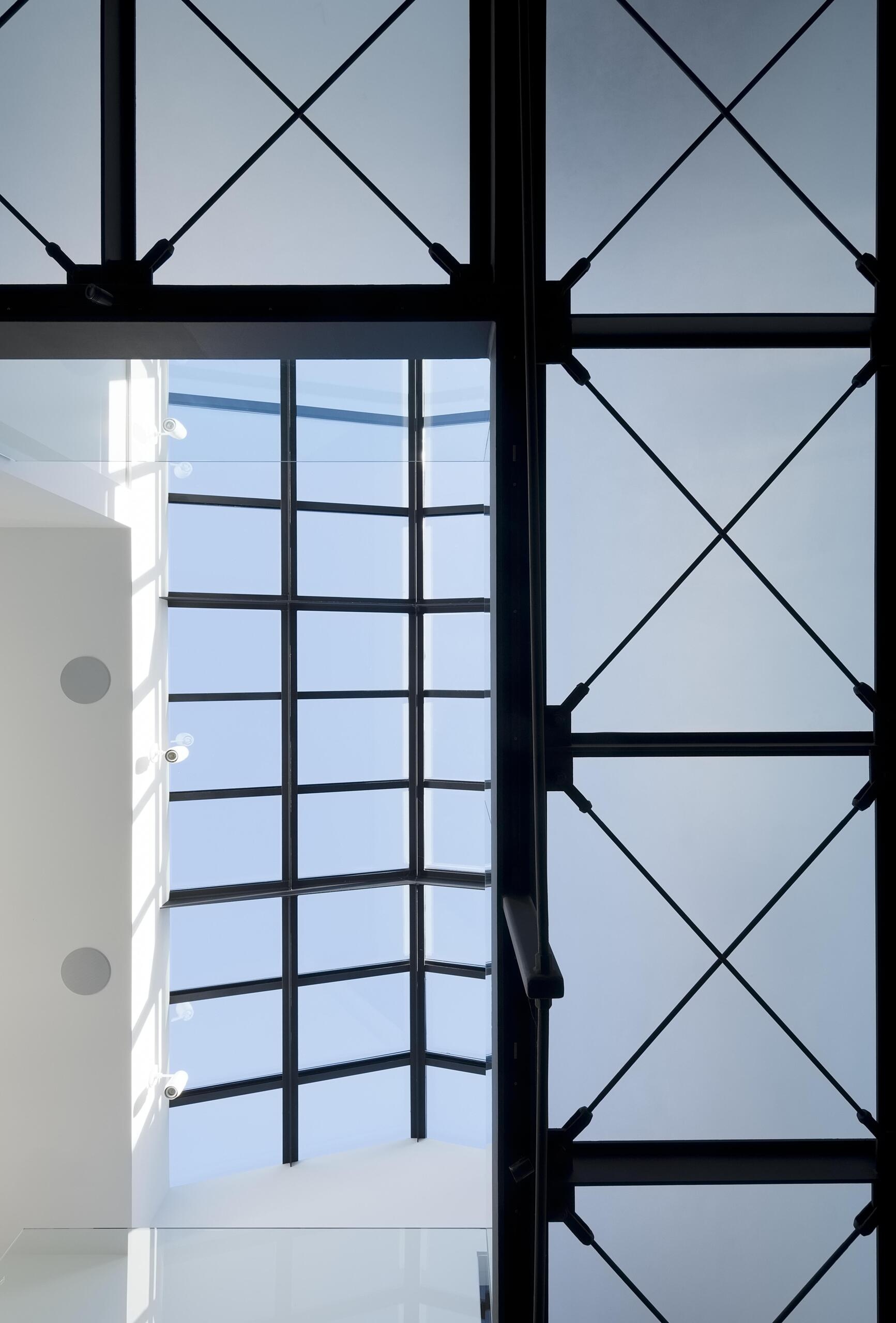 A modern interior bridge with acrylic flooring overlooking a double-height atrium, adding lightness and connection.