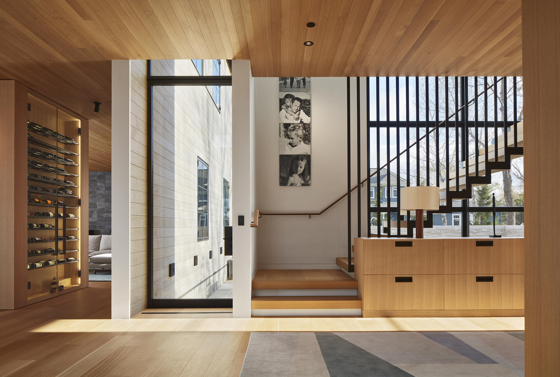 A floating steel staircase with oak treads adds a bold architectural feature to the home. Built-in cabinetry nearby provides practical storage, keeping the overall look clean and uncluttered.