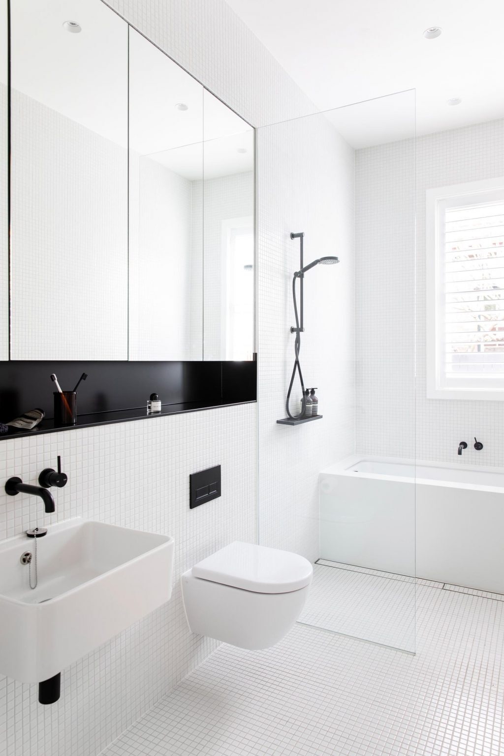 White square tiles, black accents, and a skylight create a bright, minimalist bathroom design.