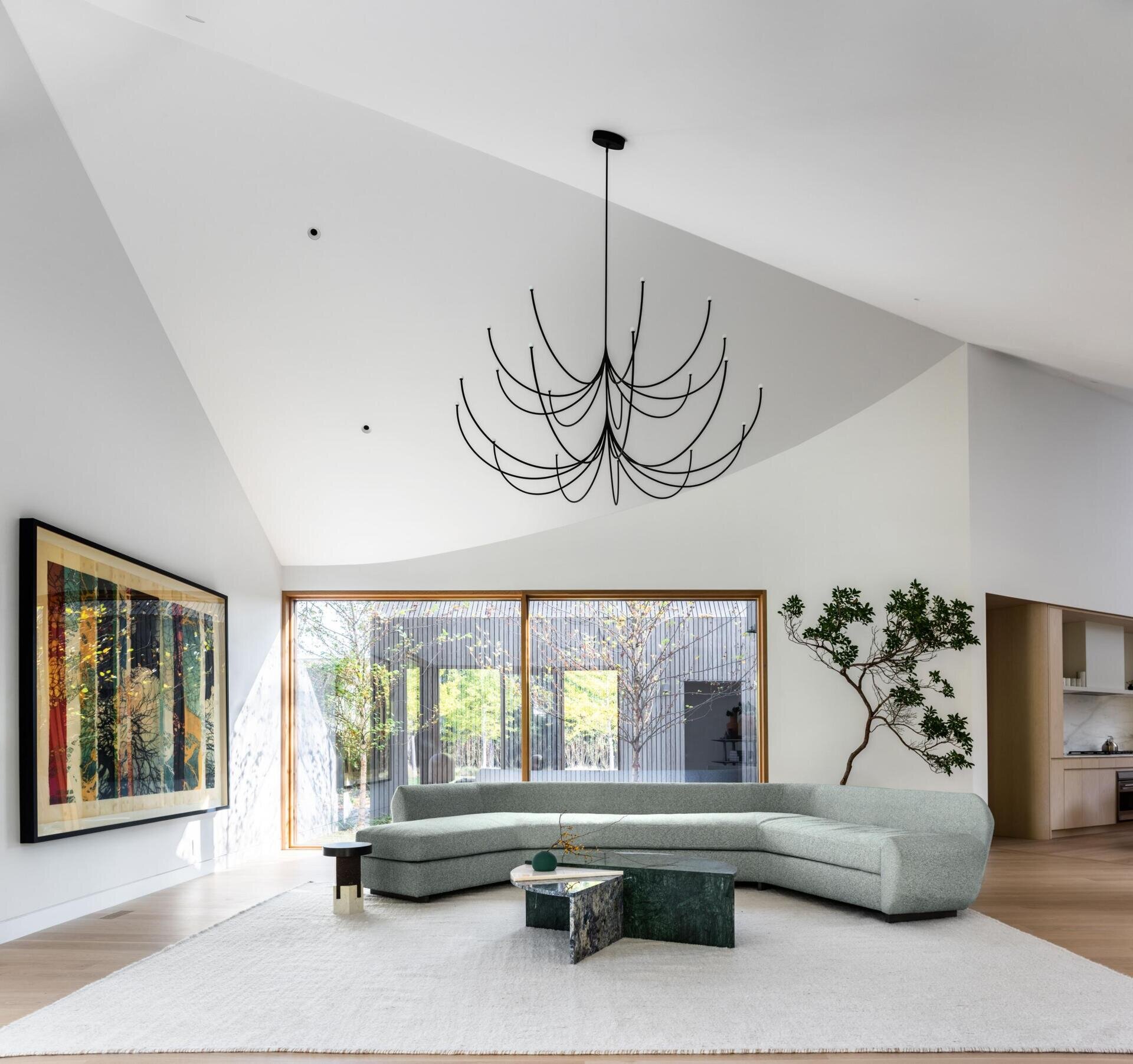 A bright white interior with angled ceilings reflects the home’s sculptural roofline, creating an open and airy atmosphere.