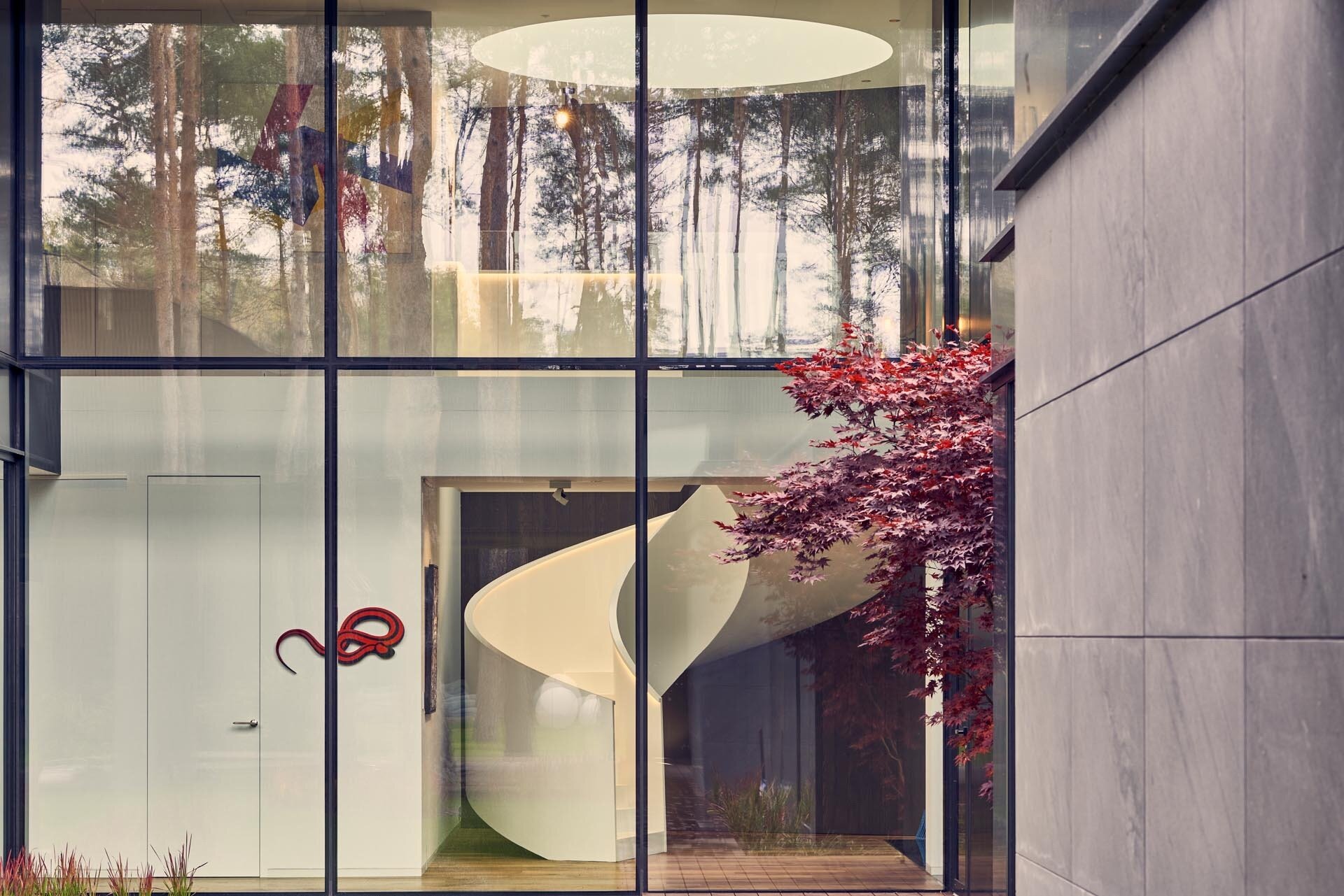 A white spiral staircase with hidden lighting becomes a sculptural centerpiece that ties both levels together.