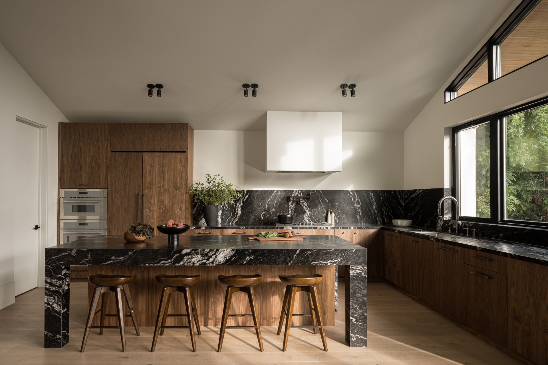 The kitchen anchors the main level, forming part of the great room alongside the breakfast nook and family lounge. It’s designed for both daily use and larger gatherings, with durable materials like leather-finished dark stone countertops and wood cabinets, adding depth and contrast.