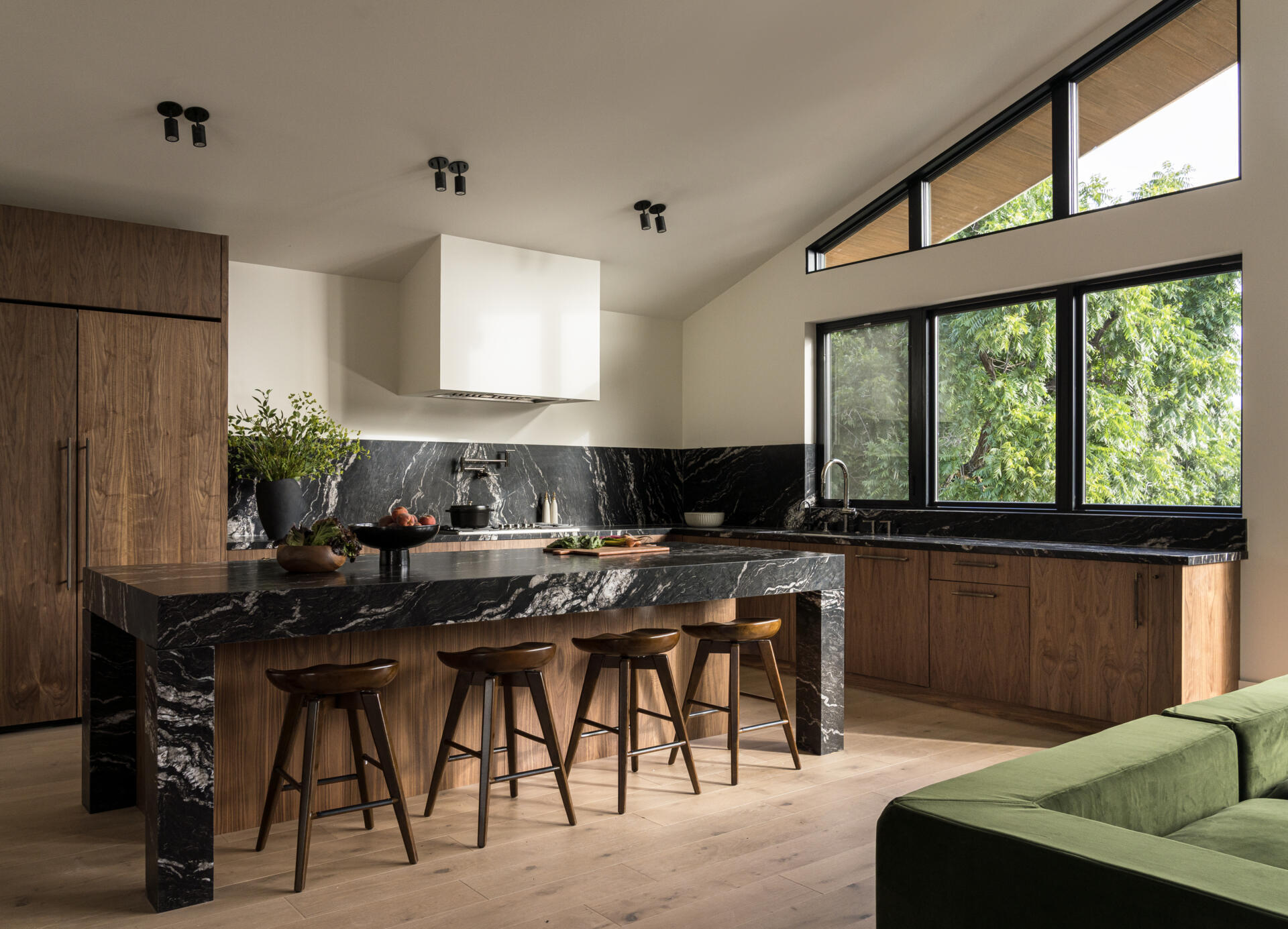 The kitchen anchors the main level, forming part of the great room alongside the breakfast nook and family lounge. It’s designed for both daily use and larger gatherings, with durable materials like leather-finished dark stone countertops and wood cabinets, adding depth and contrast.