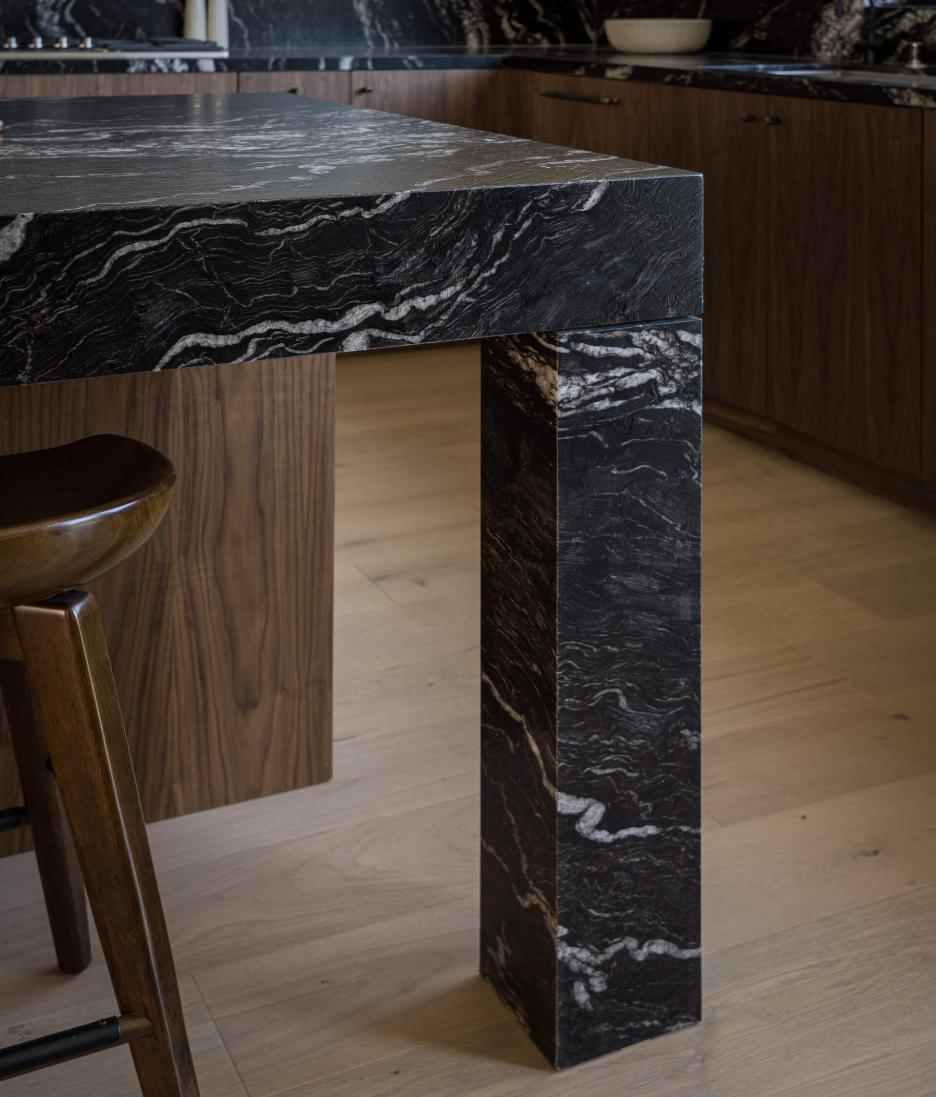 The kitchen anchors the main level, forming part of the great room alongside the breakfast nook and family lounge. It’s designed for both daily use and larger gatherings, with durable materials like leather-finished dark stone countertops and wood cabinets, adding depth and contrast.