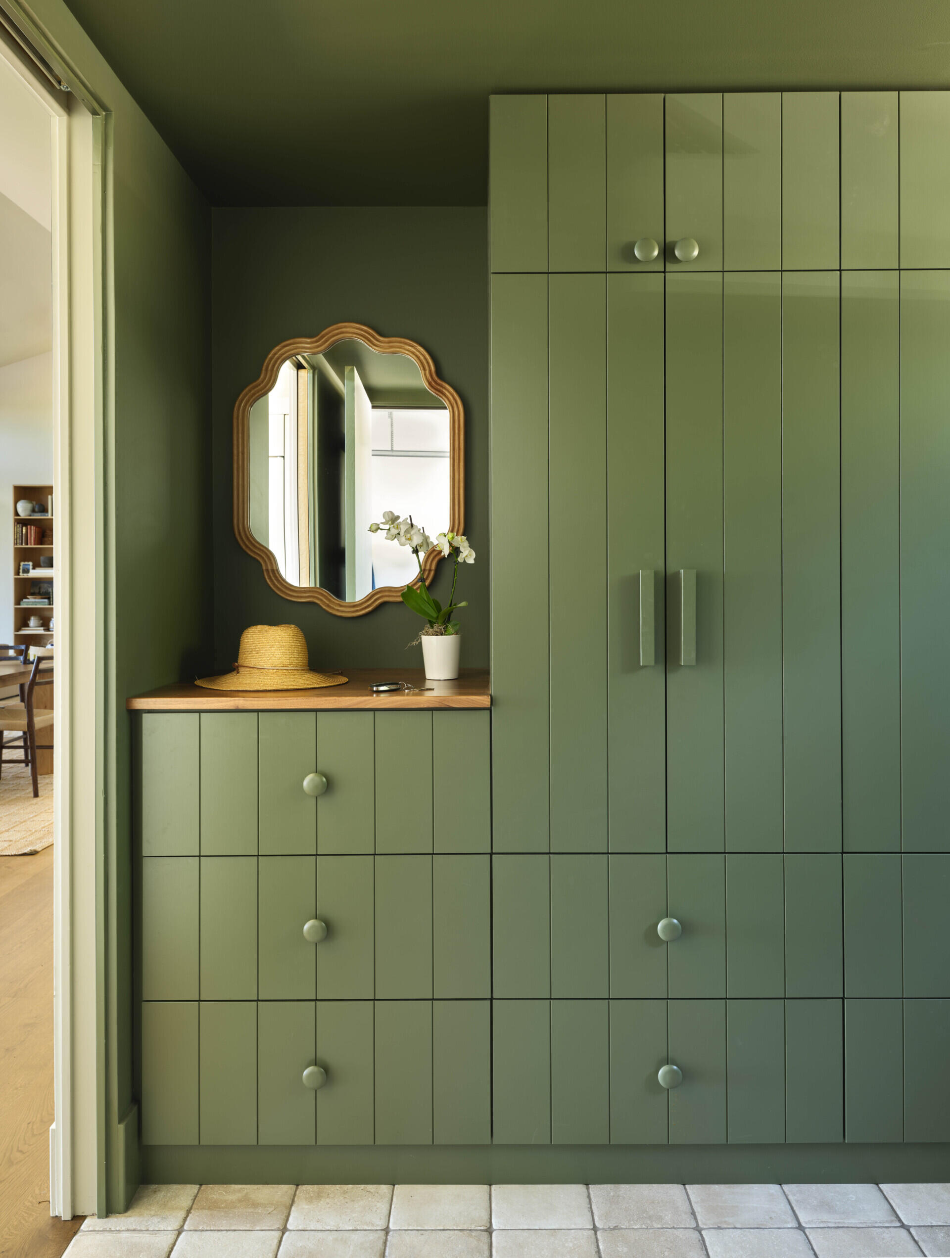 Green cabinetry and walls bring personality to a hardworking mudroom designed for daily use.