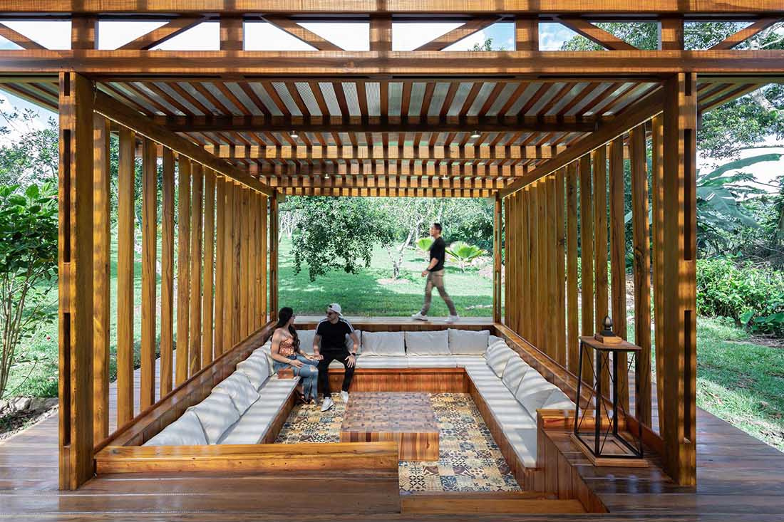 A sunken conversation pit surrounded by timber decking creates a cosy outdoor lounge that glows with soft lighting at night.