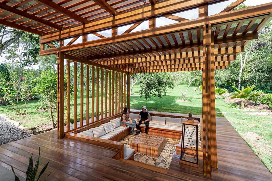 A sunken conversation pit surrounded by timber decking creates a cosy outdoor lounge that glows with soft lighting at night.