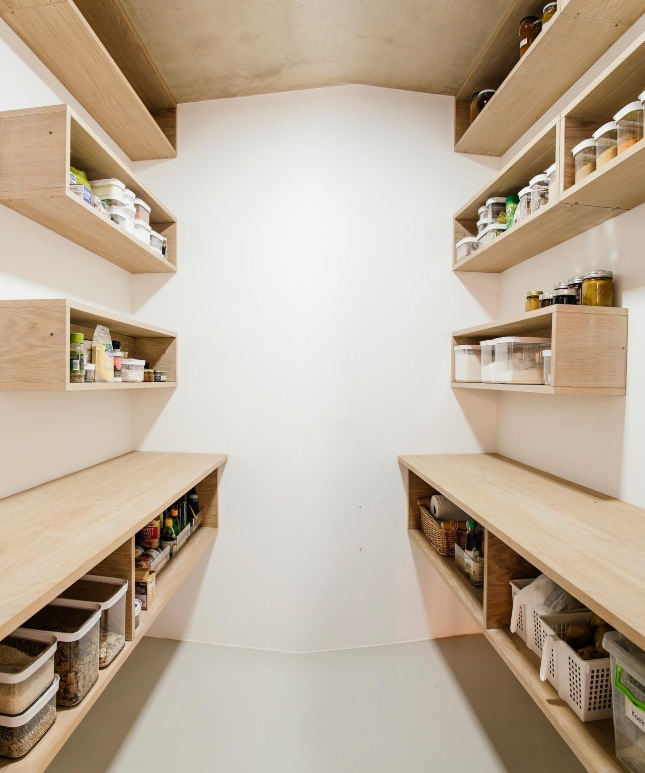 A pantry lined with wooden shelves adds practical storage without losing the warm, natural feel.