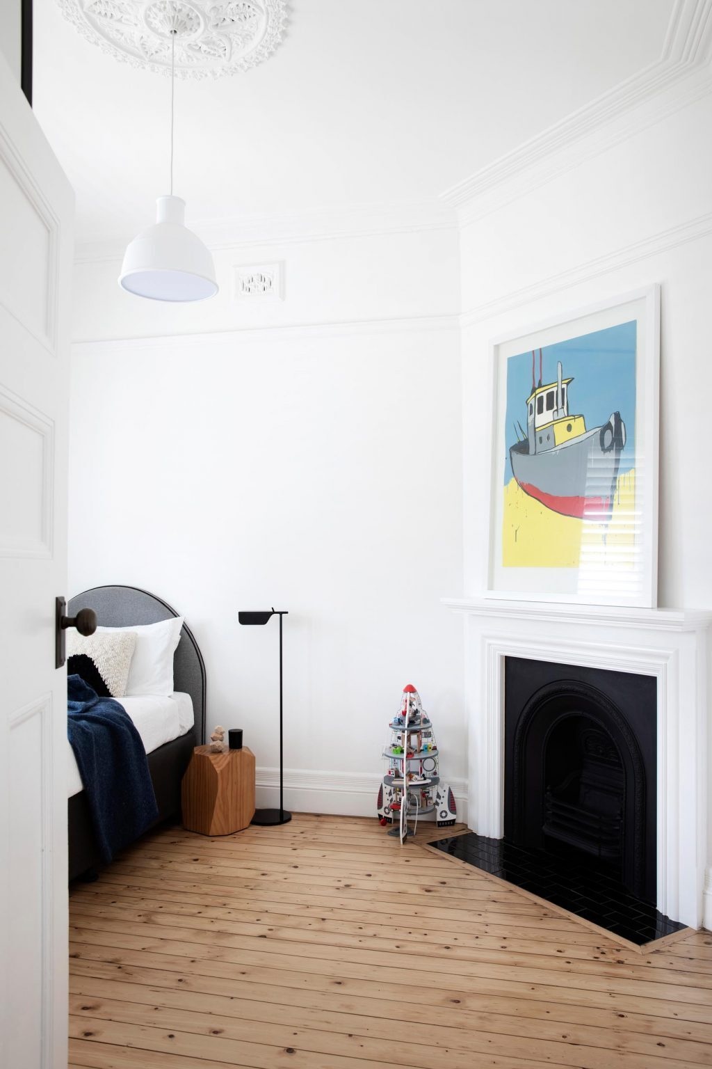 A bedroom pairs a classic cast-iron fireplace with modern furnishings for a clean, updated look.