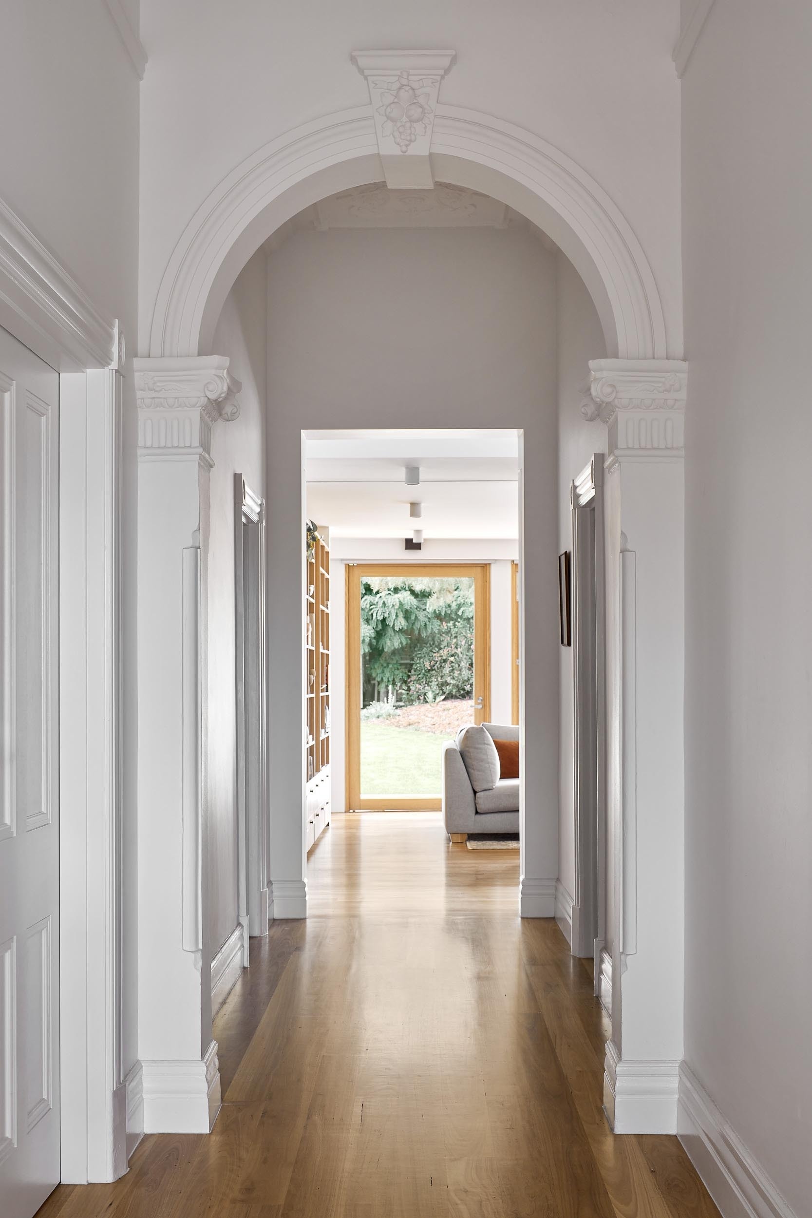 Moving through the home, the original structure reveals itself in the hallway, where older details contrast with the newer intervention. A mix of flooring adds variation underfoot, including Blackbutt timber, goat’s wool carpet, and terrazzo. These shifts help define different areas without the need for walls.